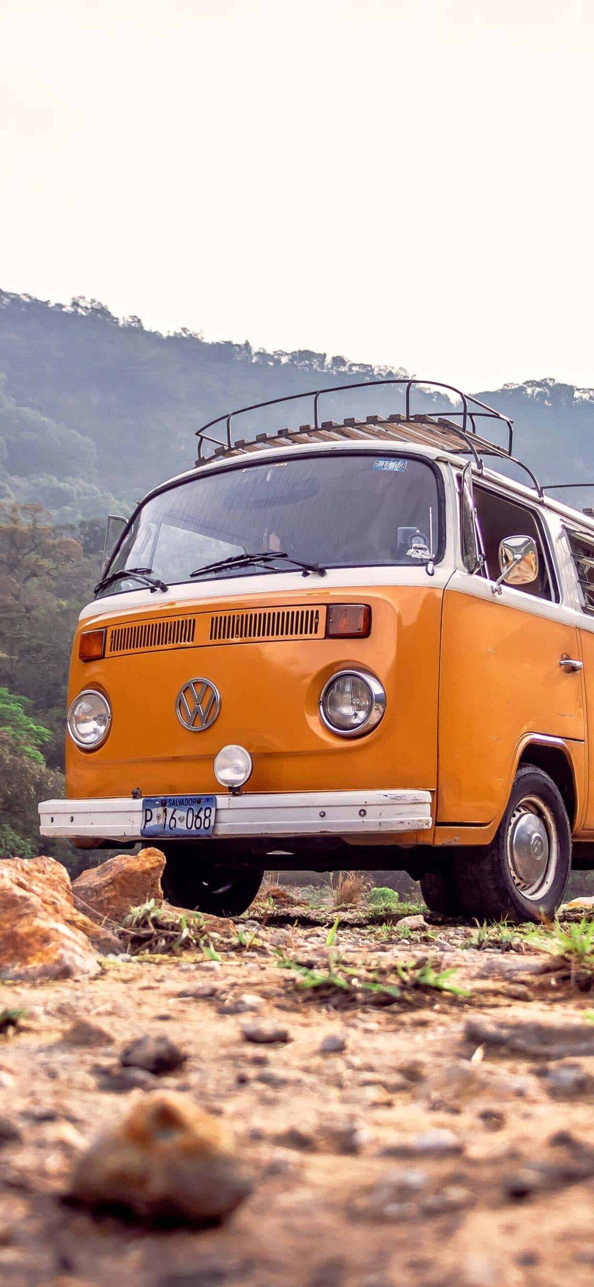 A yellow Volkswagen van is parked on a dirt road. - Vintage
