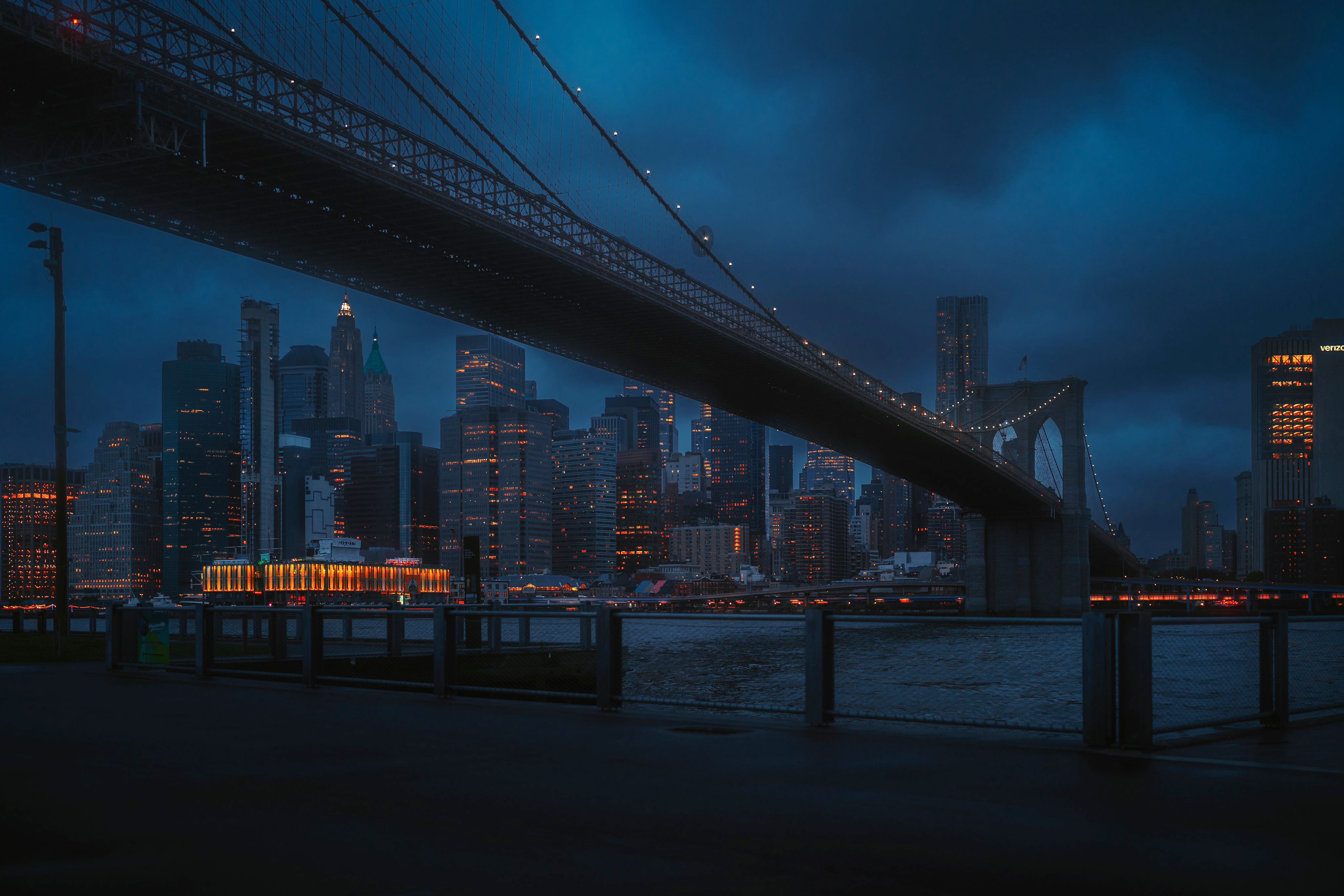 A city skyline with a suspension bridge at night - New York