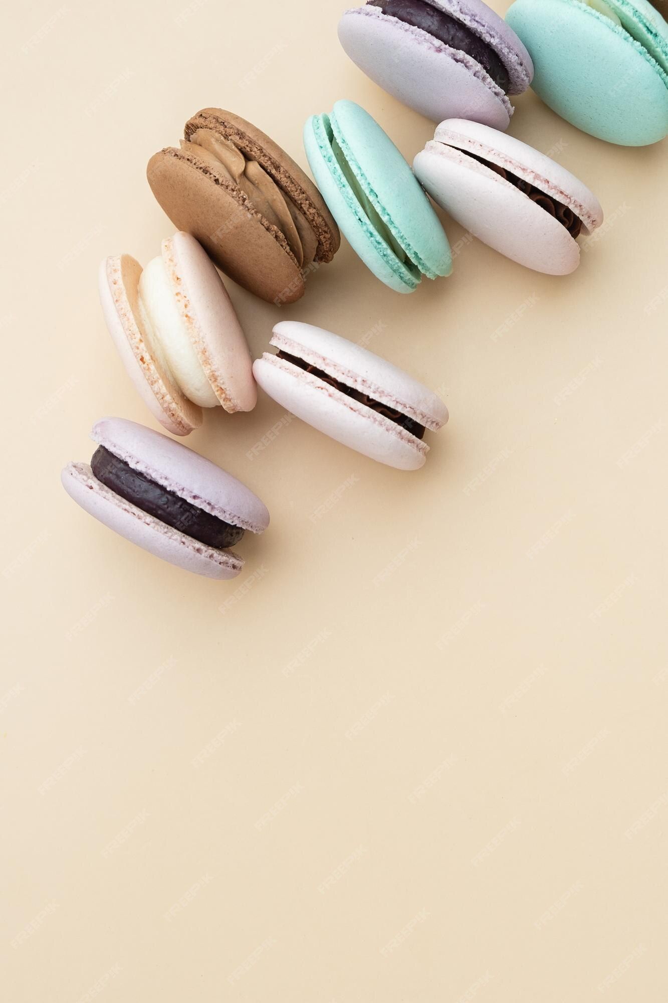Premium Photo. Different pastel colors pastry macarons top view on a beige background with copy space