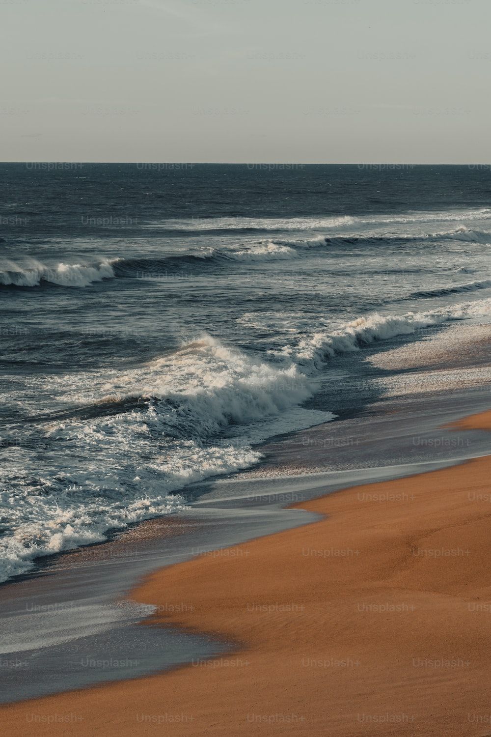 Ocean waves rolling onto a beach at sunset - Coast
