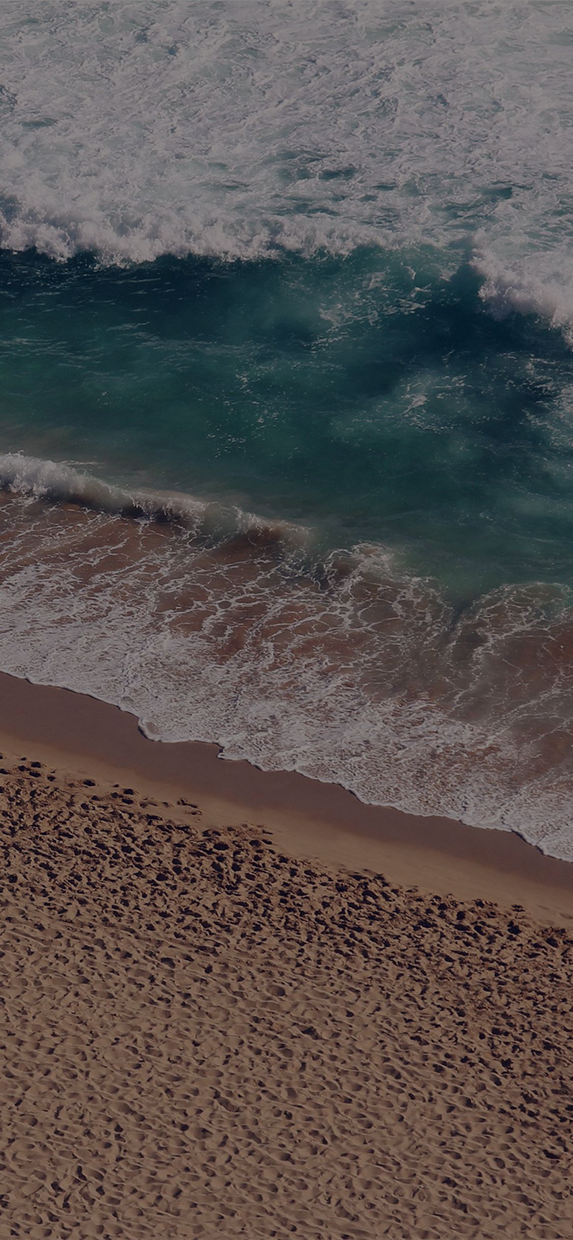 An aerial view of a sandy beach with a wave crashing on the shore - Coast