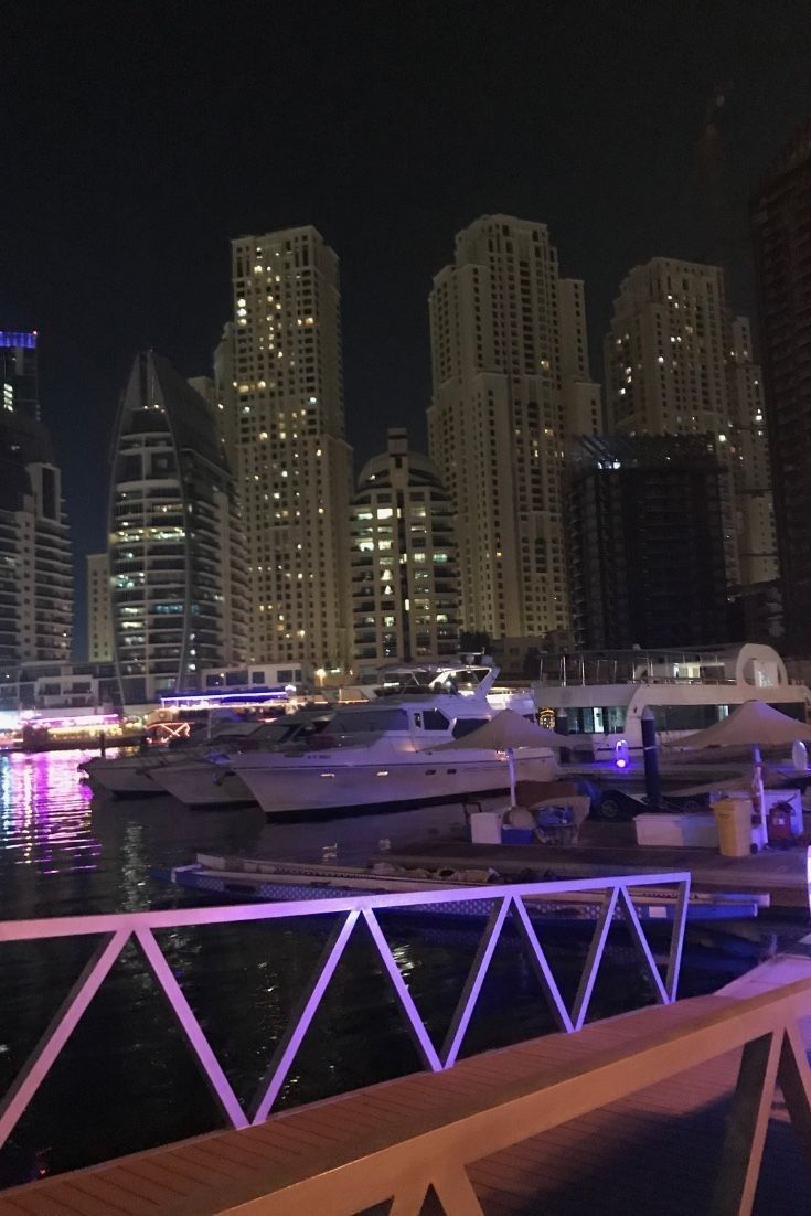 A night time view of the Dubai marina with boats and lights. - Dubai