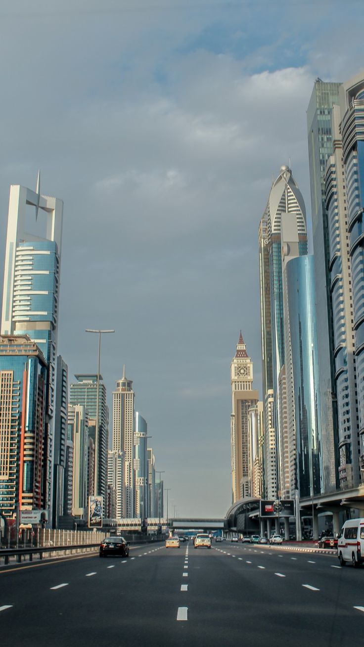 A city street with cars and tall buildings on both sides. - Dubai