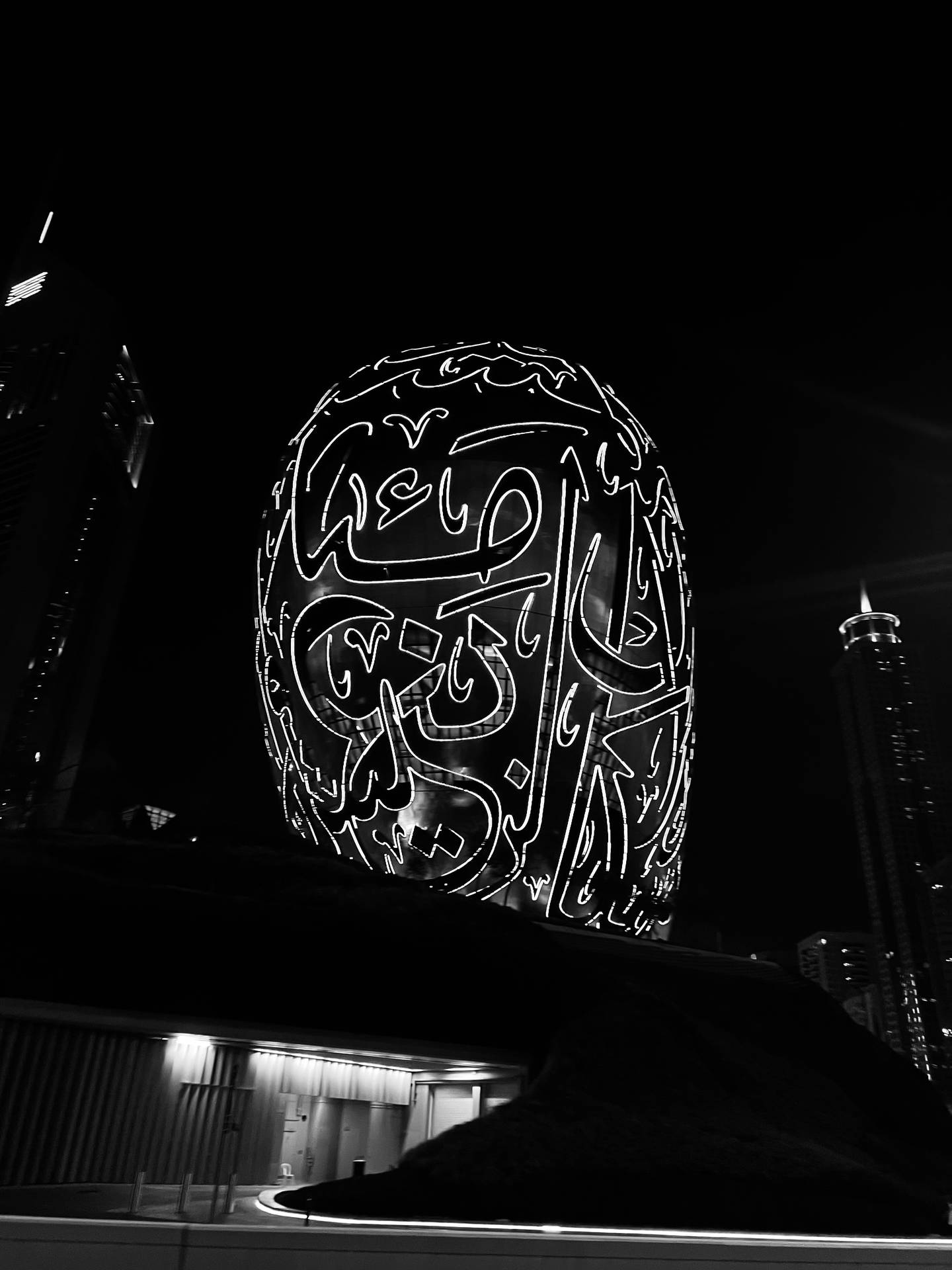 Black and white photo of a large lit up sign in Arabic script - Dubai