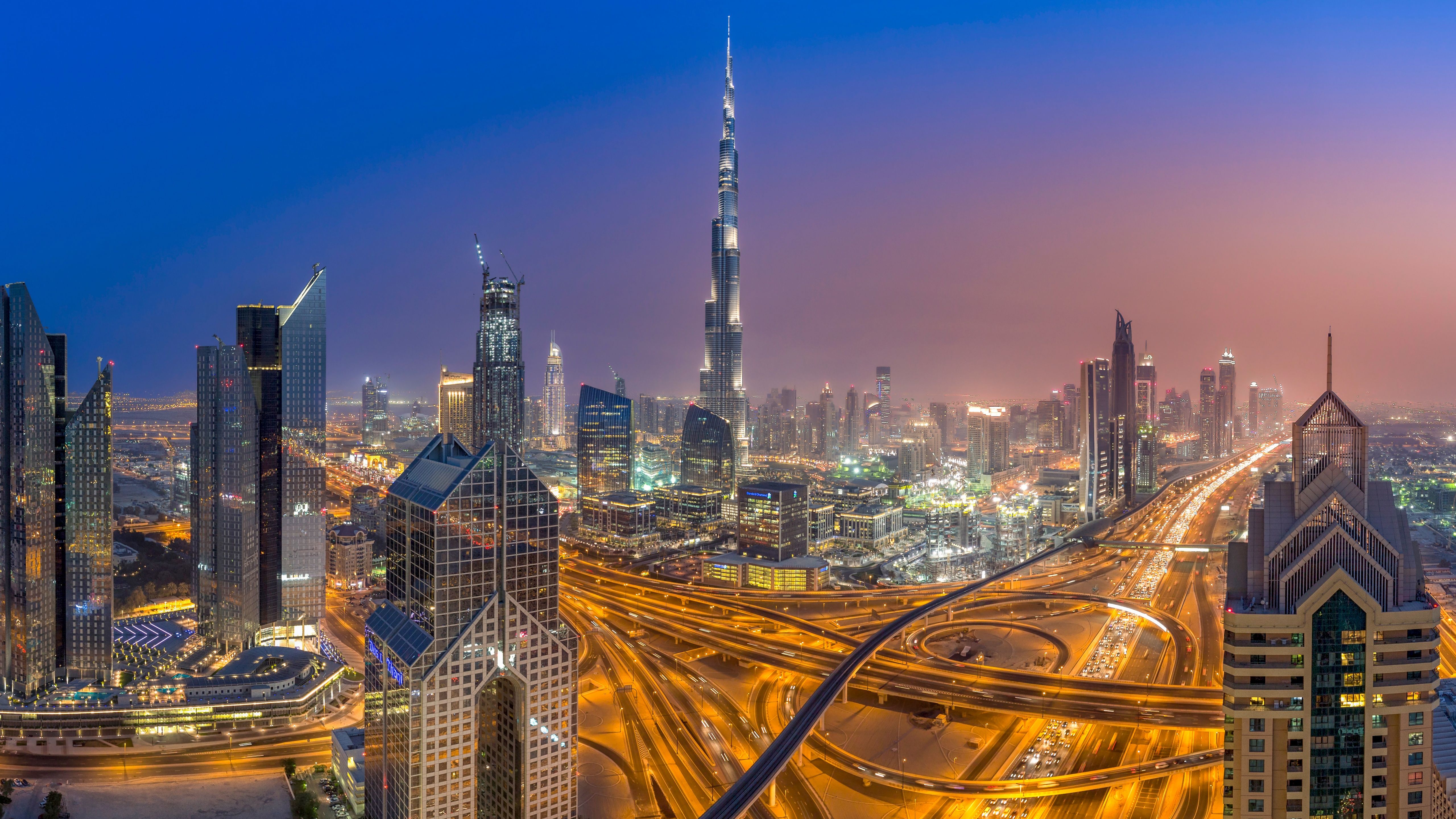 A cityscape at night with a highway and skyscrapers. - Dubai