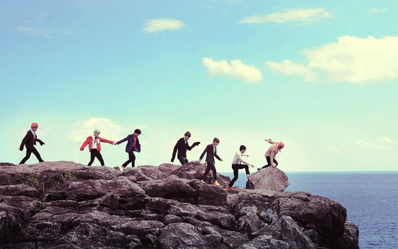 BTS standing on a rock in a scene from their music video for 'DNA' - Coast