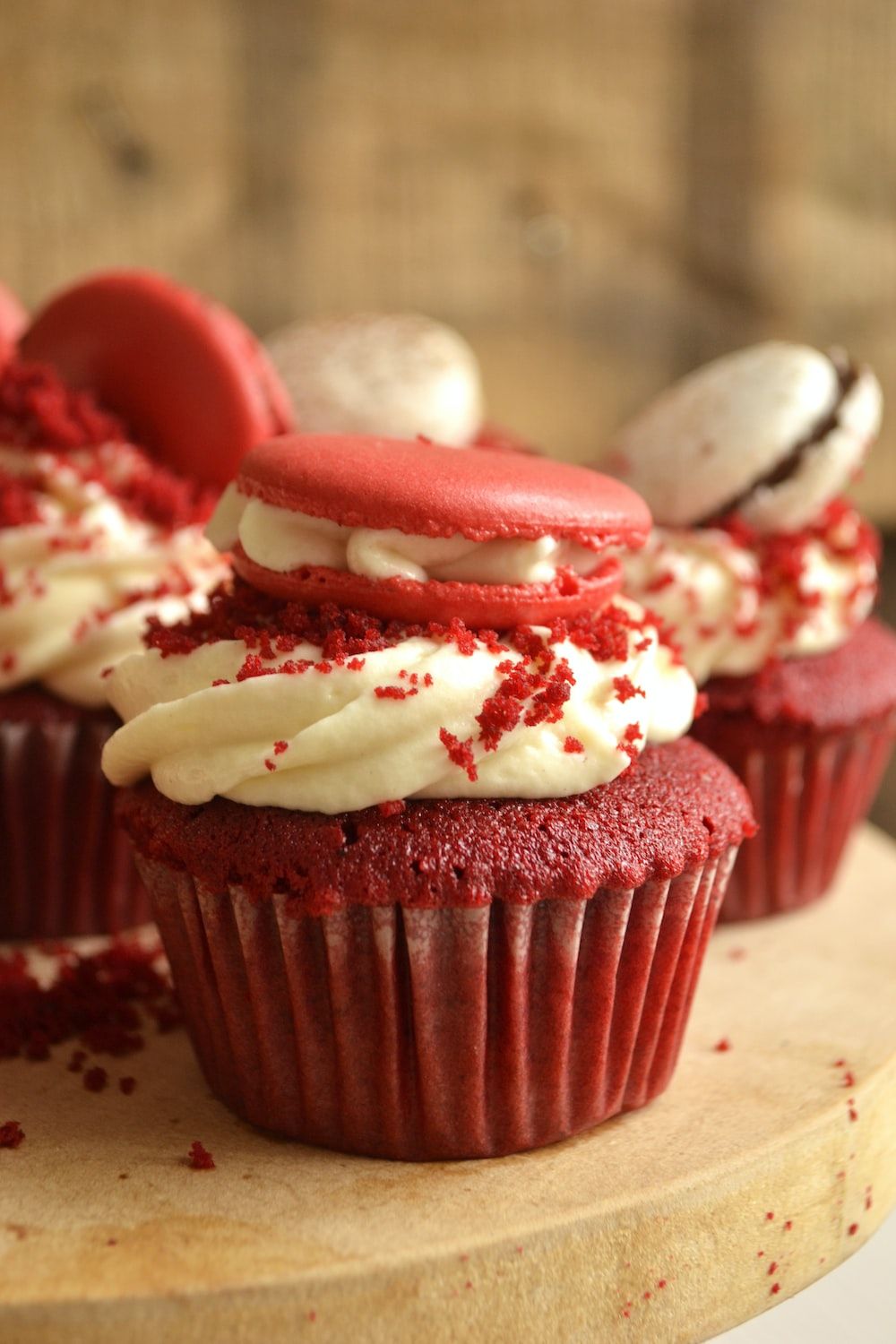 Red velvet cupcakes with a swirl of white frosting and a red velvet macaron on top. - Cupcakes