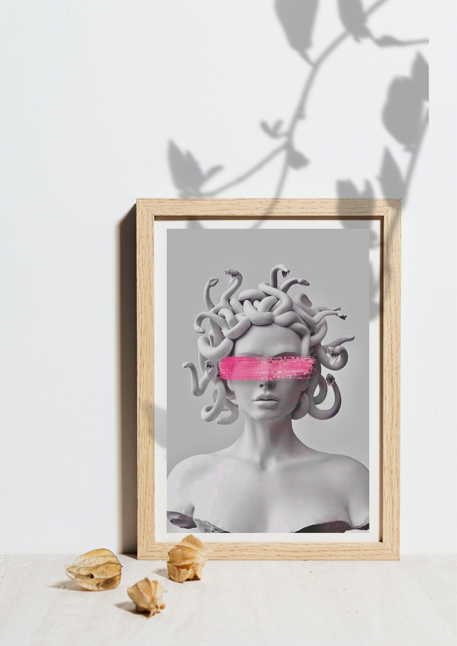 A framed art print of a gorgon with pink tape over her eyes - Medusa