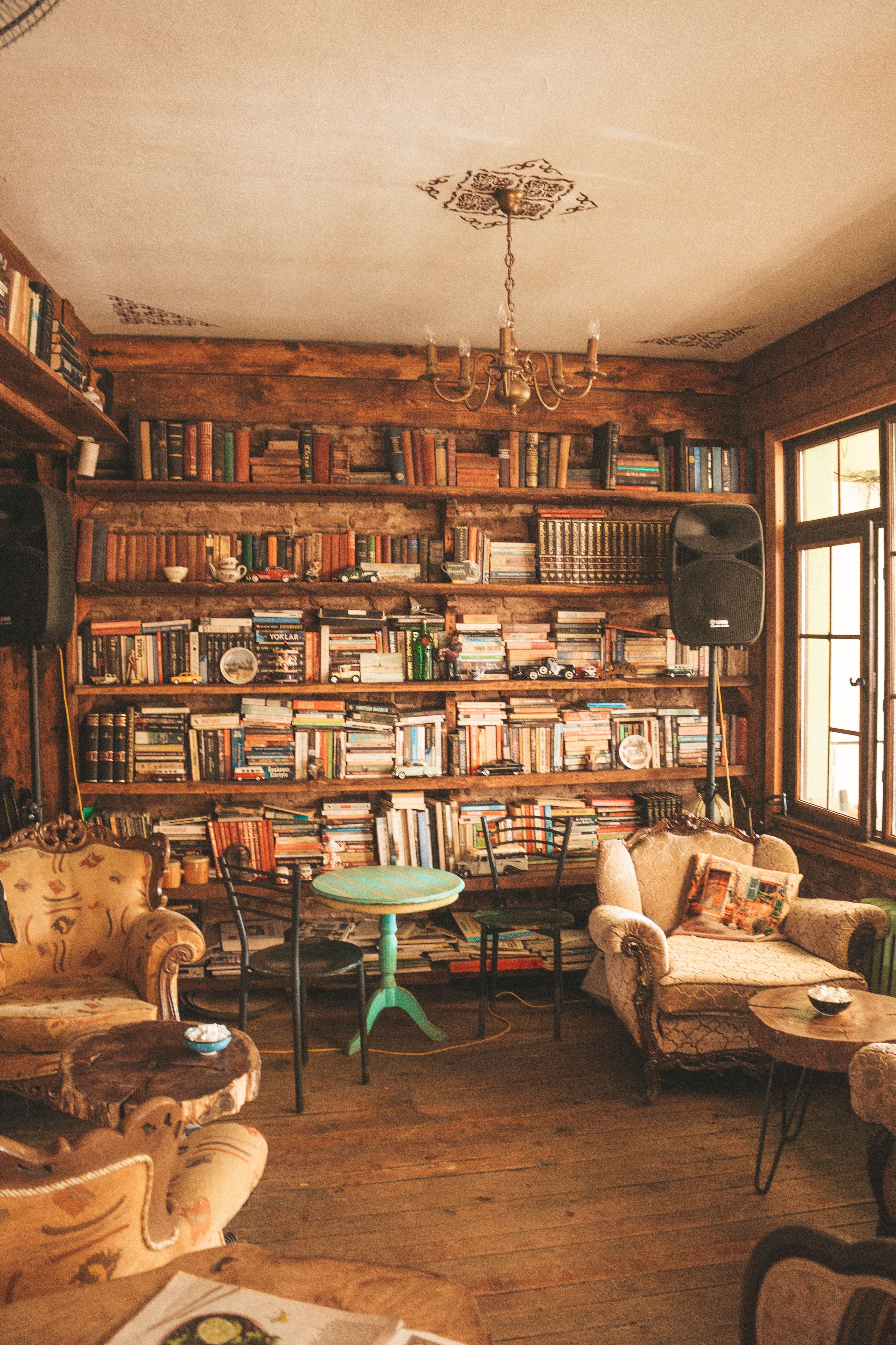 A room with bookshelves full of books, tables, chairs, and couches. - Bookshelf