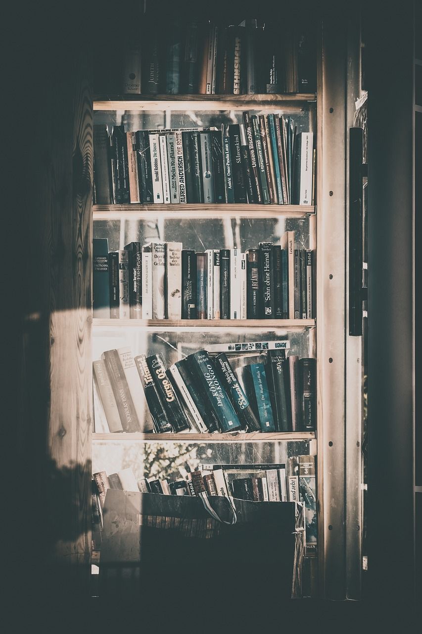 A bookshelf with many books in a phone booth. - Bookshelf