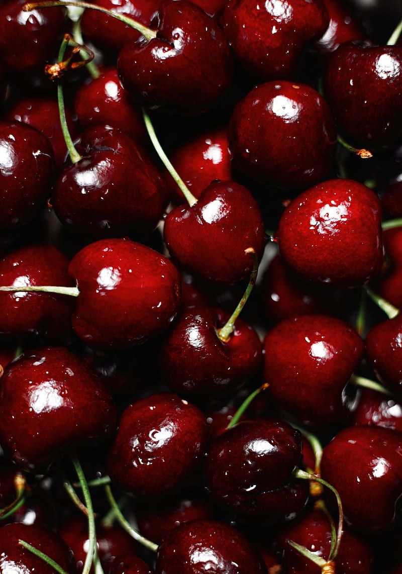 A pile of cherries with stems, against a black background. - Cherry