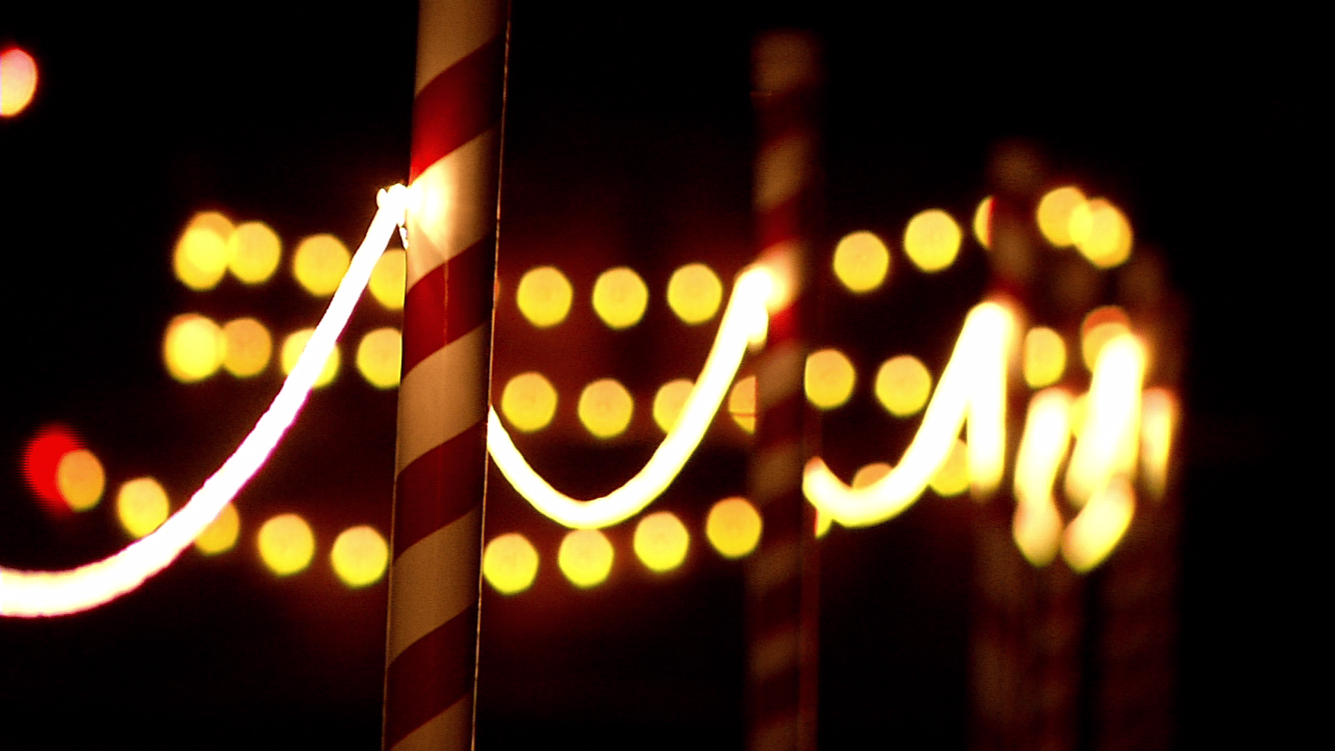 A pole with red and white stripes is lit up at night. - Christmas lights, fairy lights