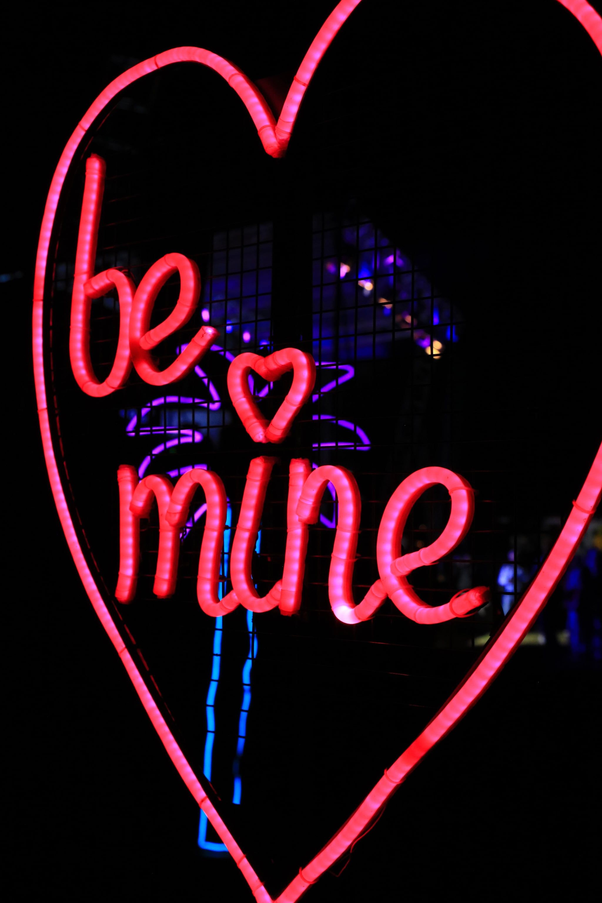 A red neon sign in the shape of a heart that says 