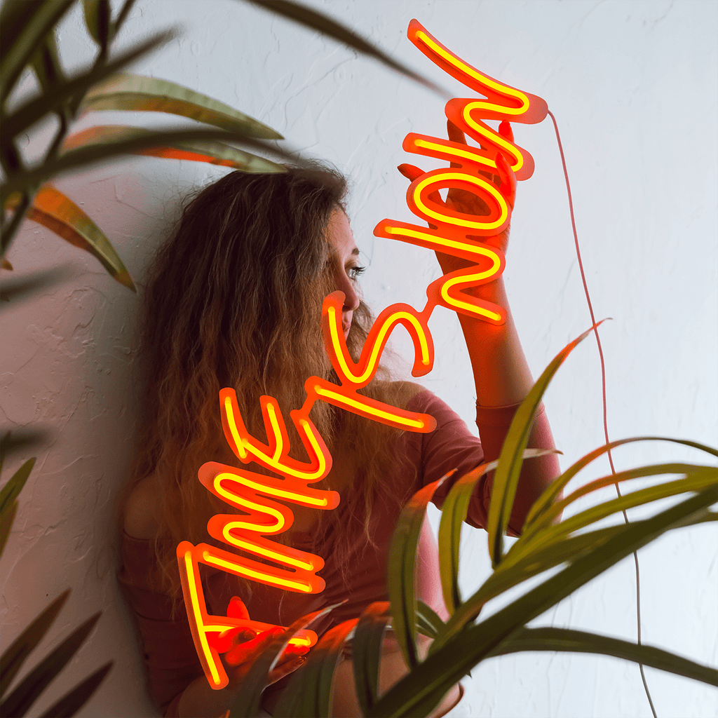 A woman sitting in front of a wall with a neon sign that says 'After Show' - Neon orange
