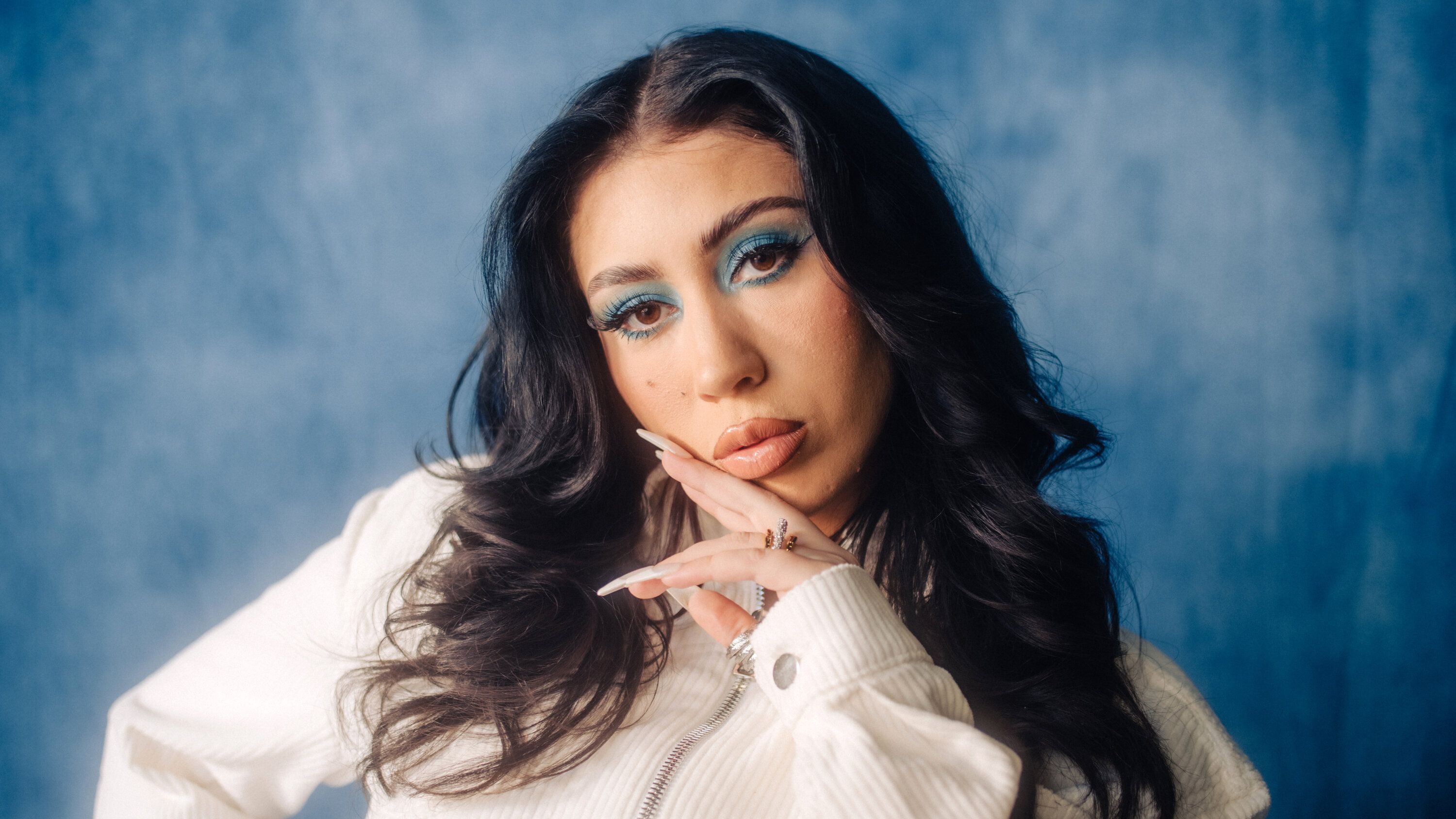 Rising pop star, Kiana Ledé, poses in front of a blue background - Kali Uchis