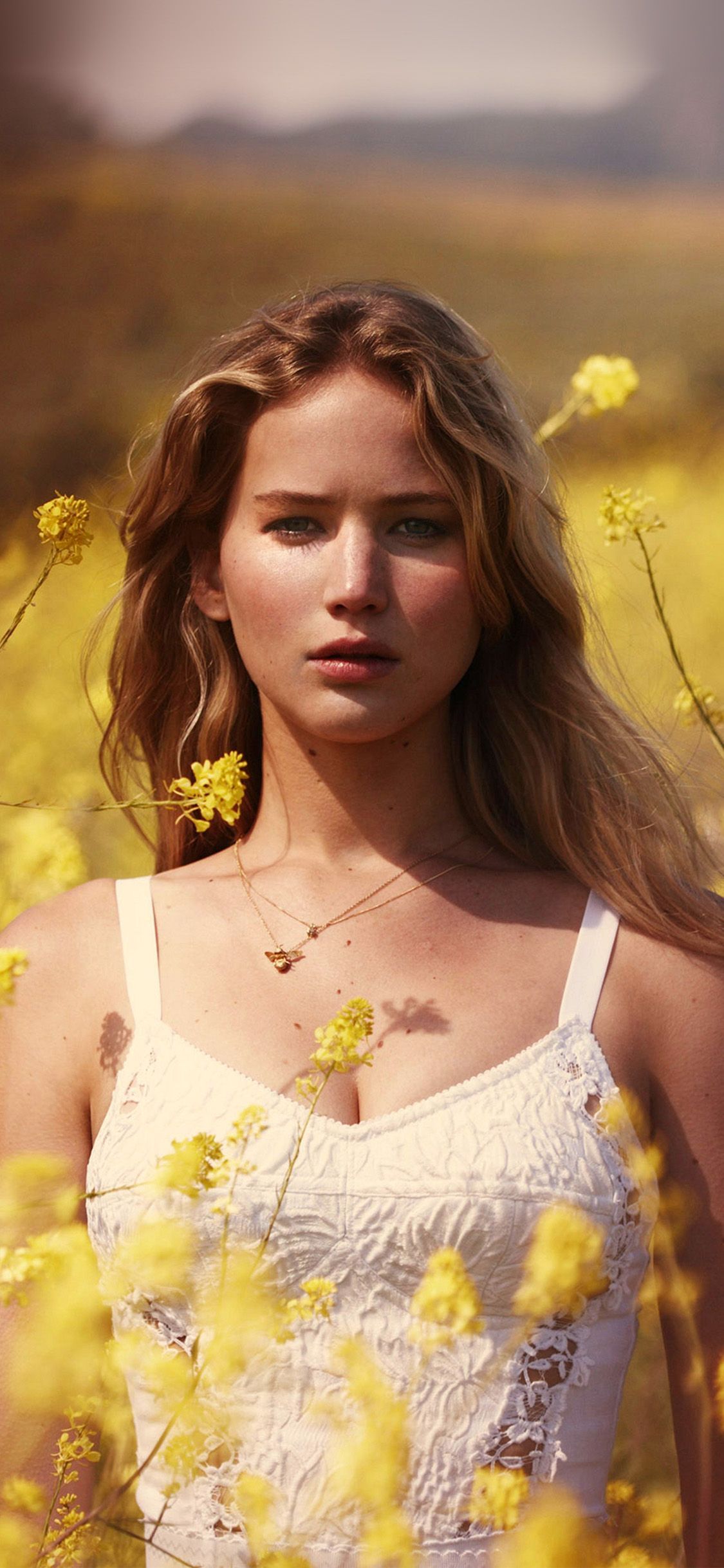 Jennifer Lawrence standing in a field of yellow flowers - Jennifer Lawrence