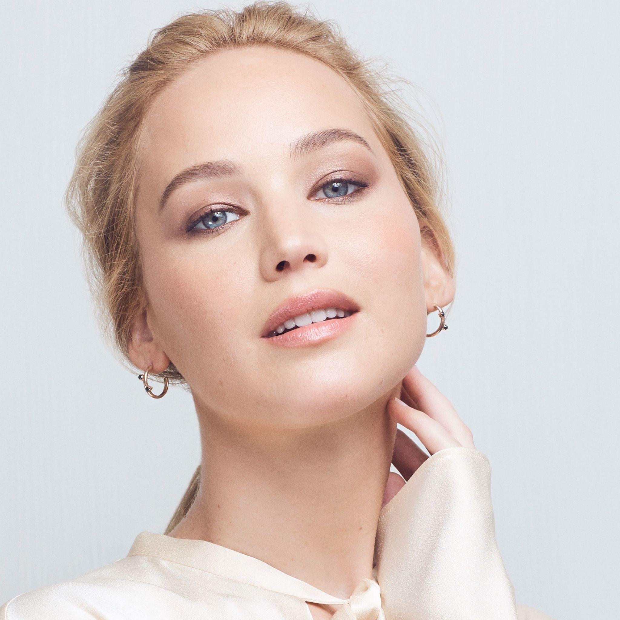 Jennifer Lawrence wearing a white top and gold hoop earrings - Jennifer Lawrence