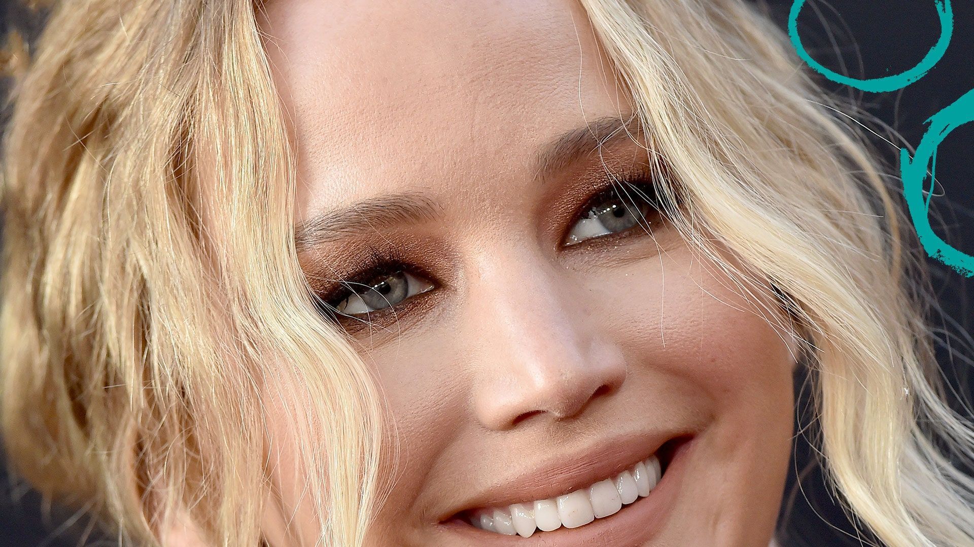 Closeup of a blonde woman with smoky eyes smiling at the camera - Jennifer Lawrence