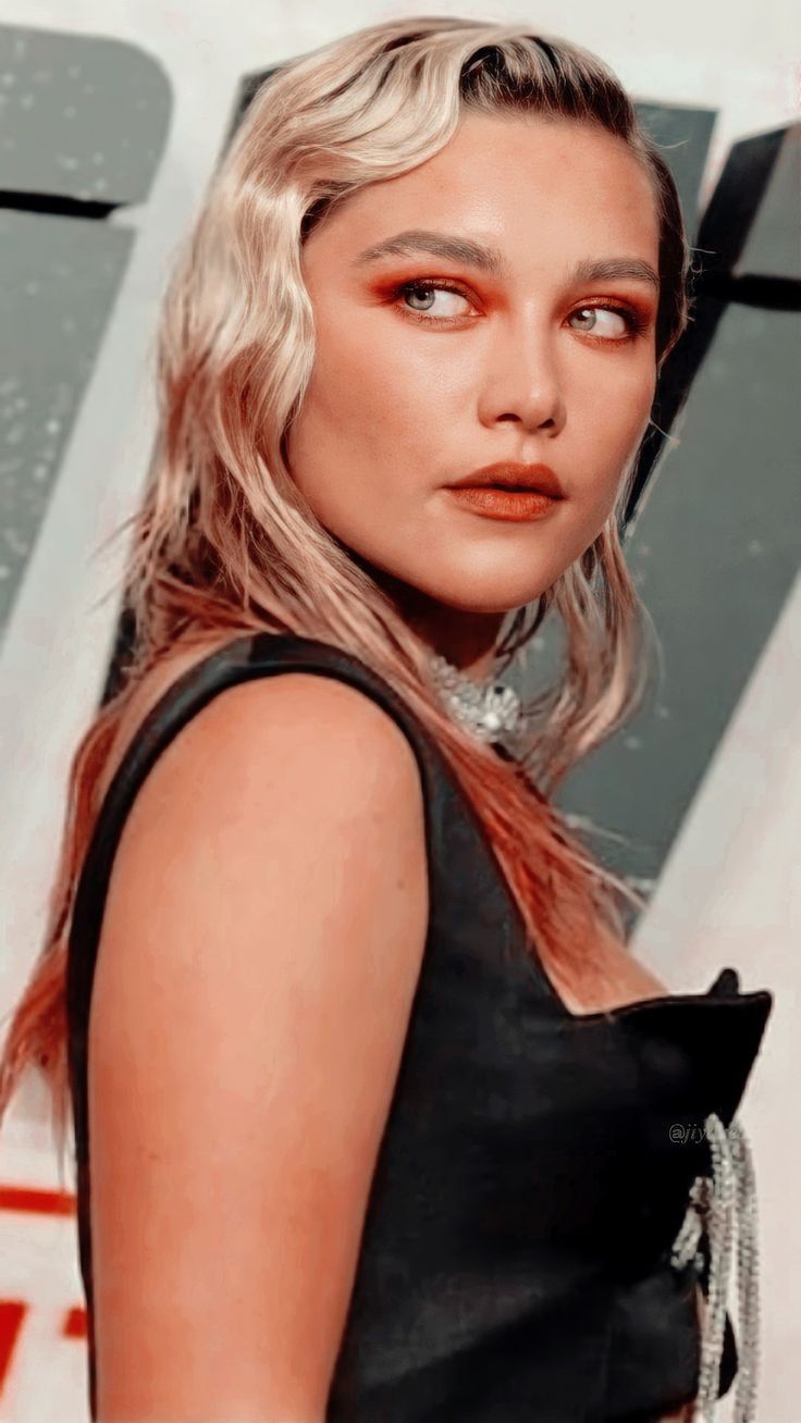 Close up of model with blonde hair and orange eyeshadow looking to the side - Florence Pugh
