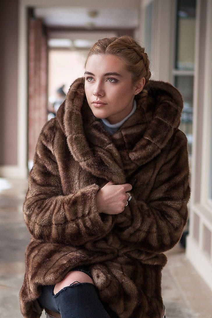 A woman wearing a fur coat is looking at the camera. - Florence Pugh