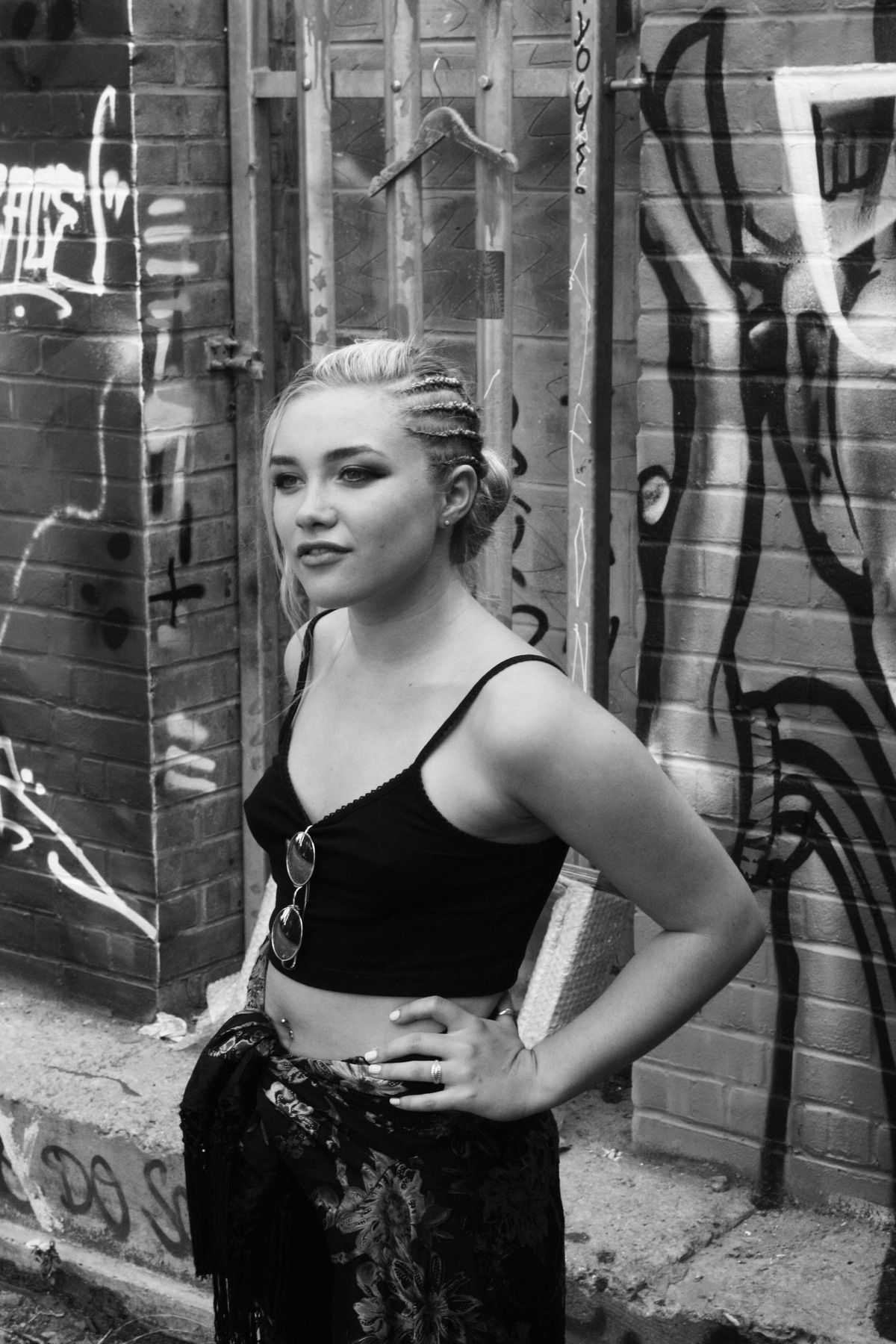 A woman with her hands on her hips in front of a graffiti wall. - Florence Pugh