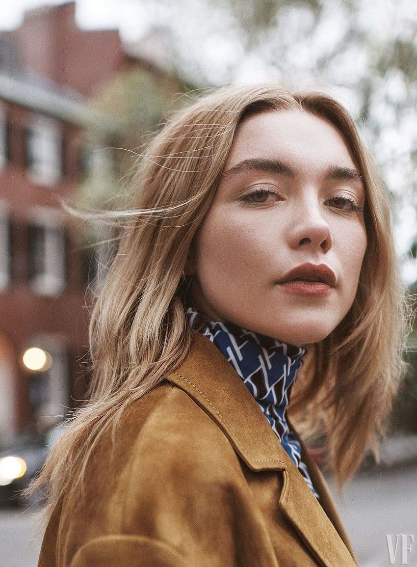 Close up of Saoirse Ronan looking into the camera with a building in the background - Florence Pugh