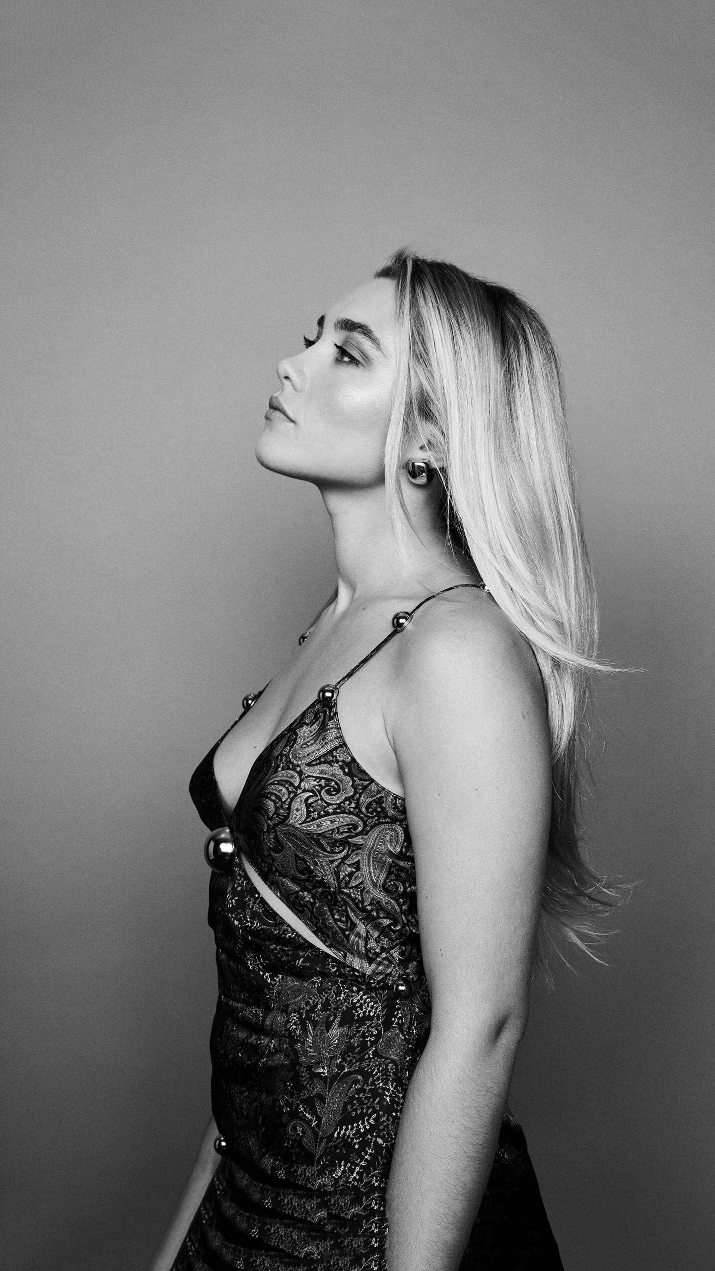 A black and white photo of a blonde woman in a black dress looking up - Florence Pugh