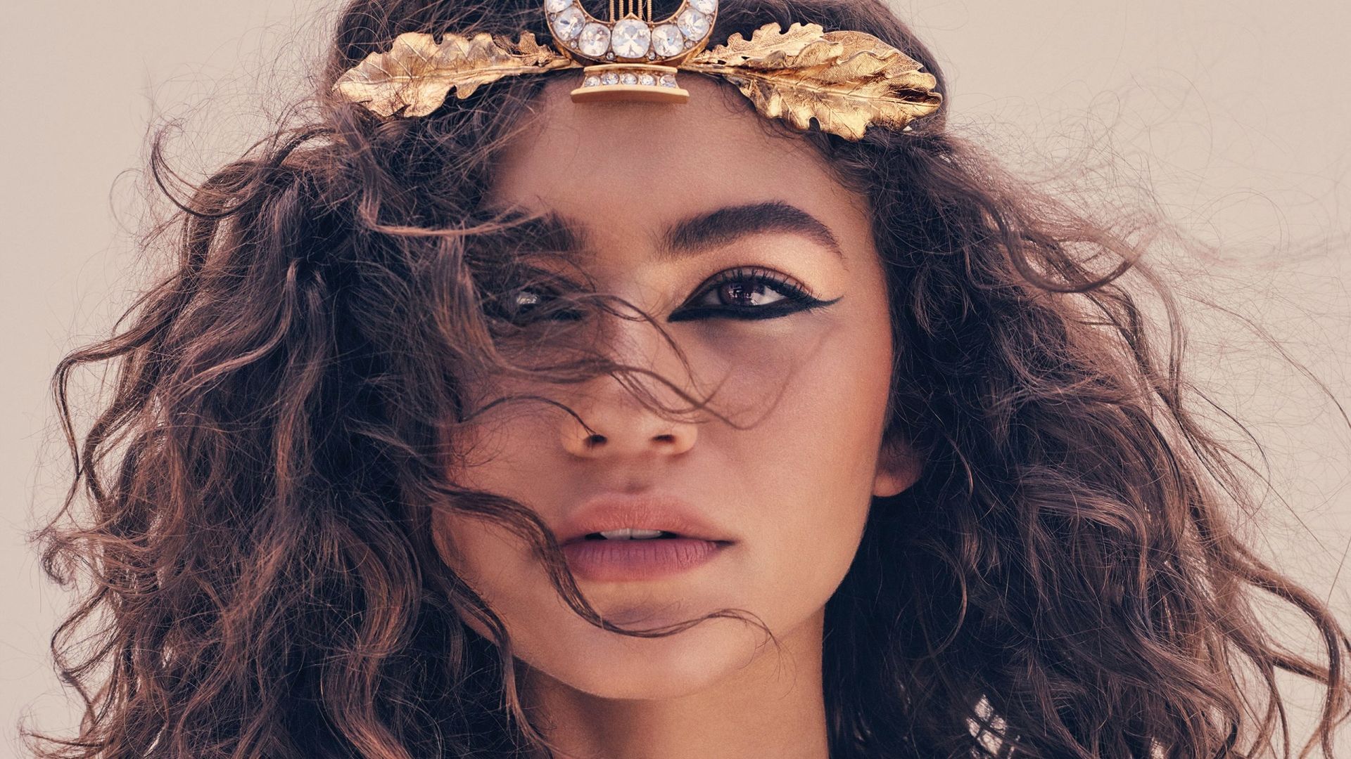 Zendaya wears a gold leaf headband and has her curly hair blowing in the wind. - Zendaya