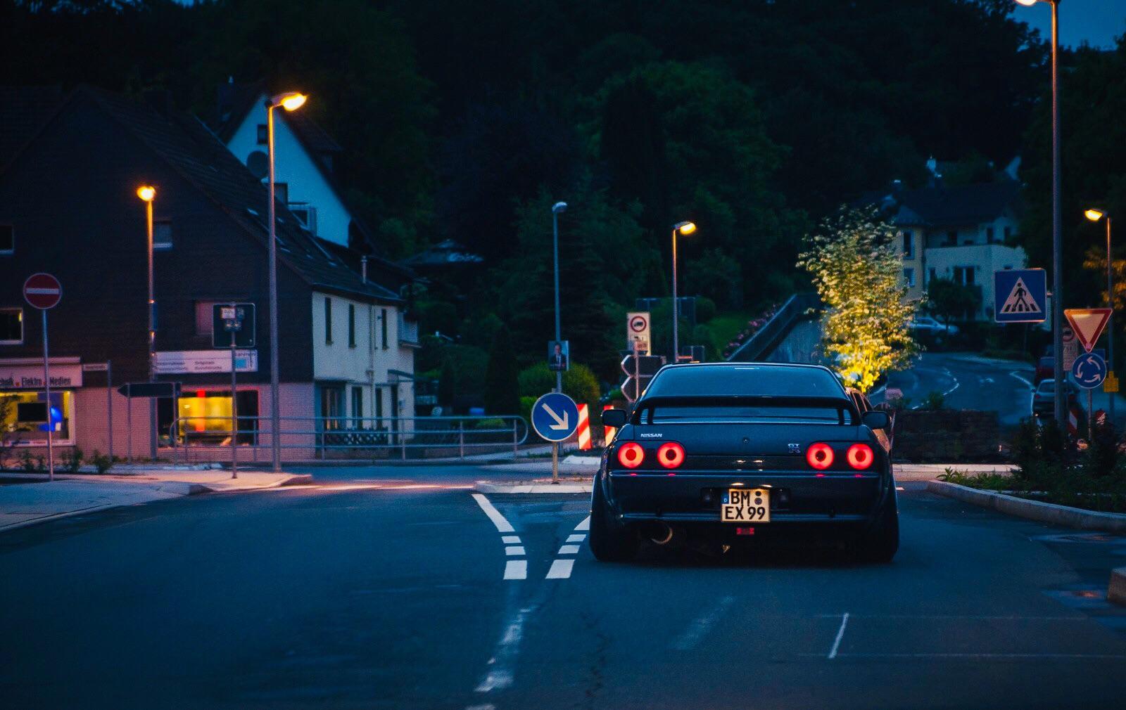 A car driving down a street at night - Nissan Skyline, skyline