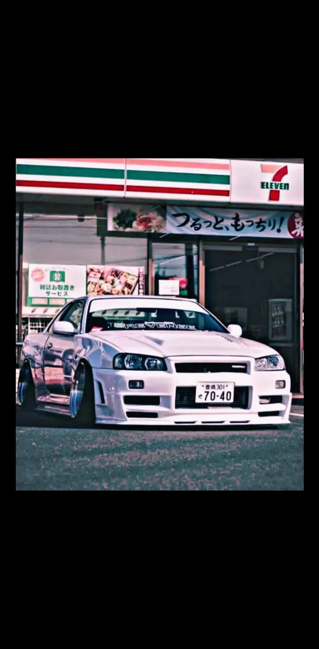 A white car parked in front of a gas station - Nissan Skyline