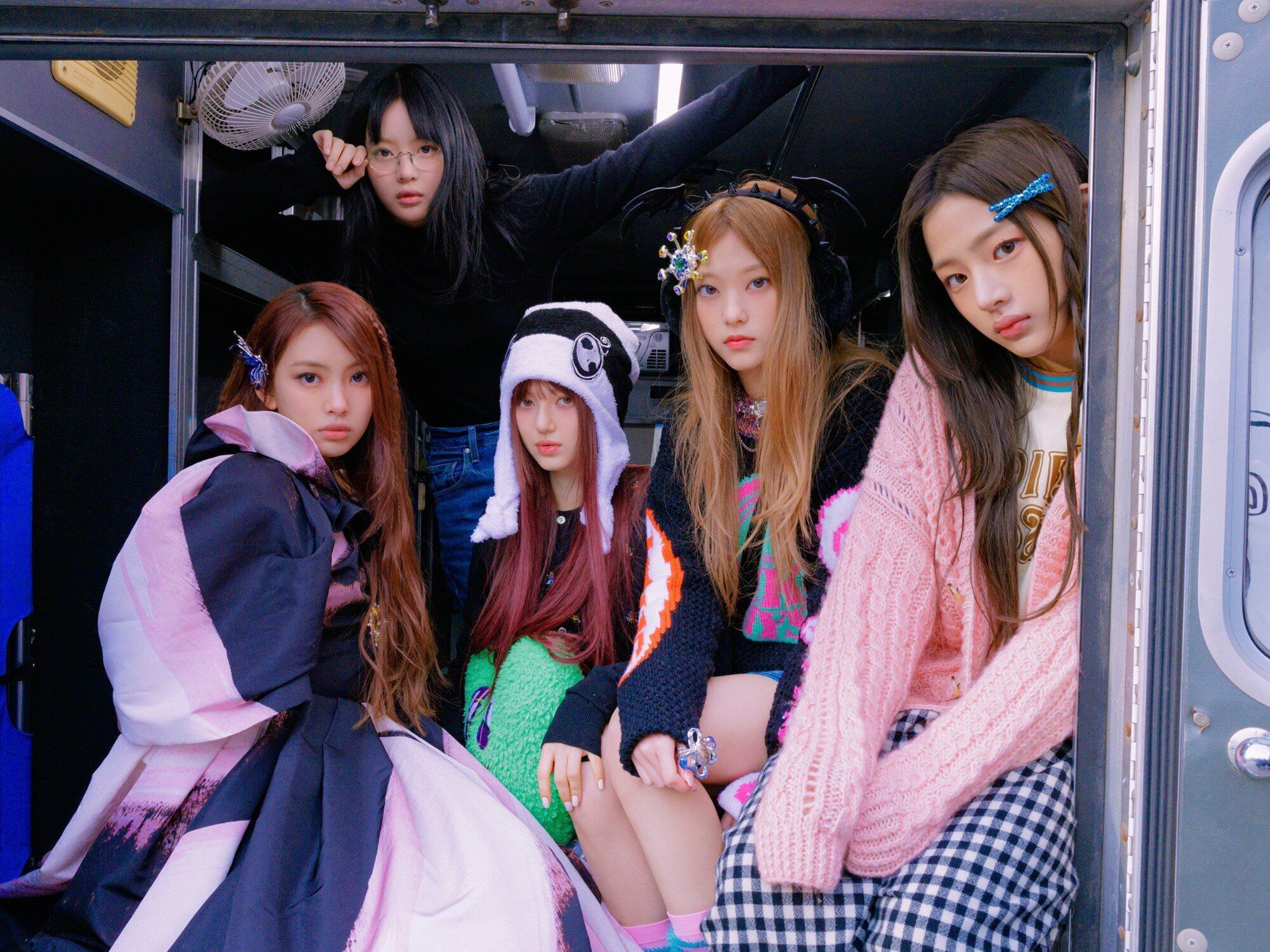 ITZY members sitting in the back of a truck - NewJeans
