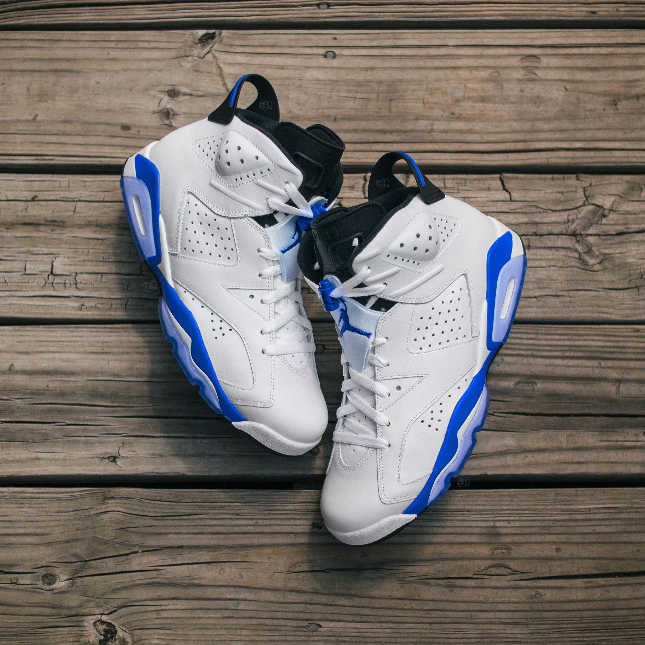 A pair of white and blue Air Jordan 6 sneakers on a wooden floor - Air Jordan 6