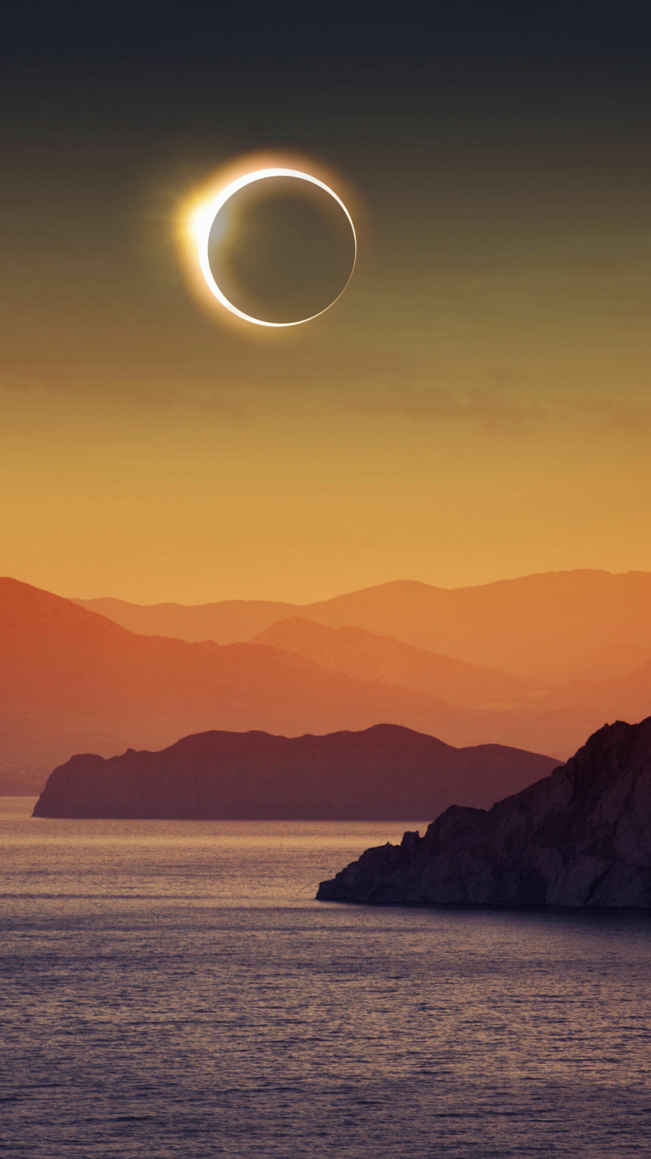 An eclipse over a body of water with mountains in the background - Eclipse