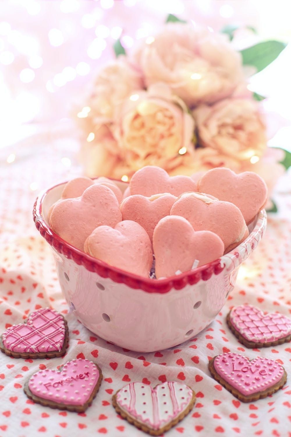 Pink heart-shaped cookies in a bowl with flowers in the background. - Valentine's Day