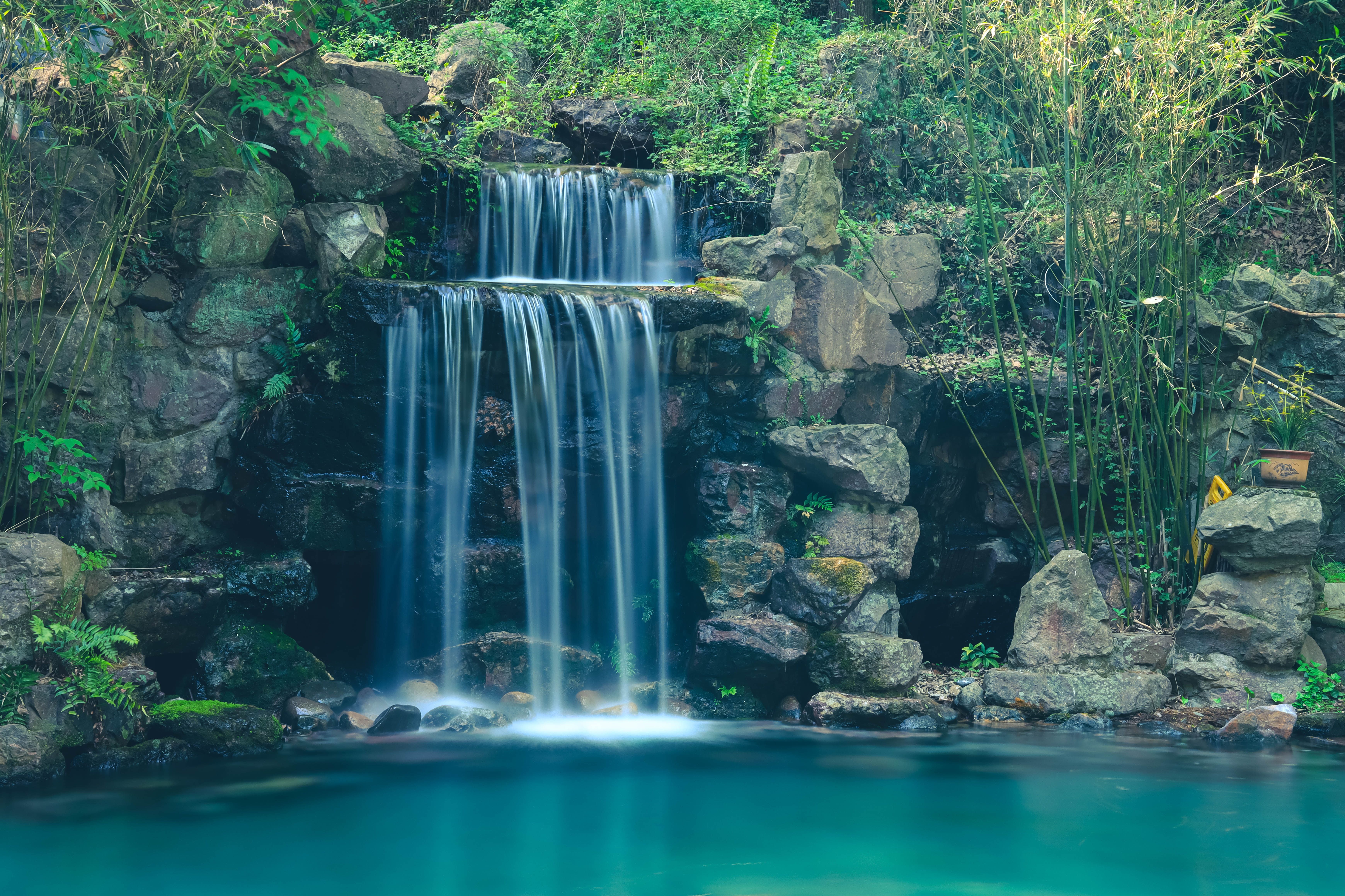 A waterfall flowing into a pond surrounded by greenery - Waterfall