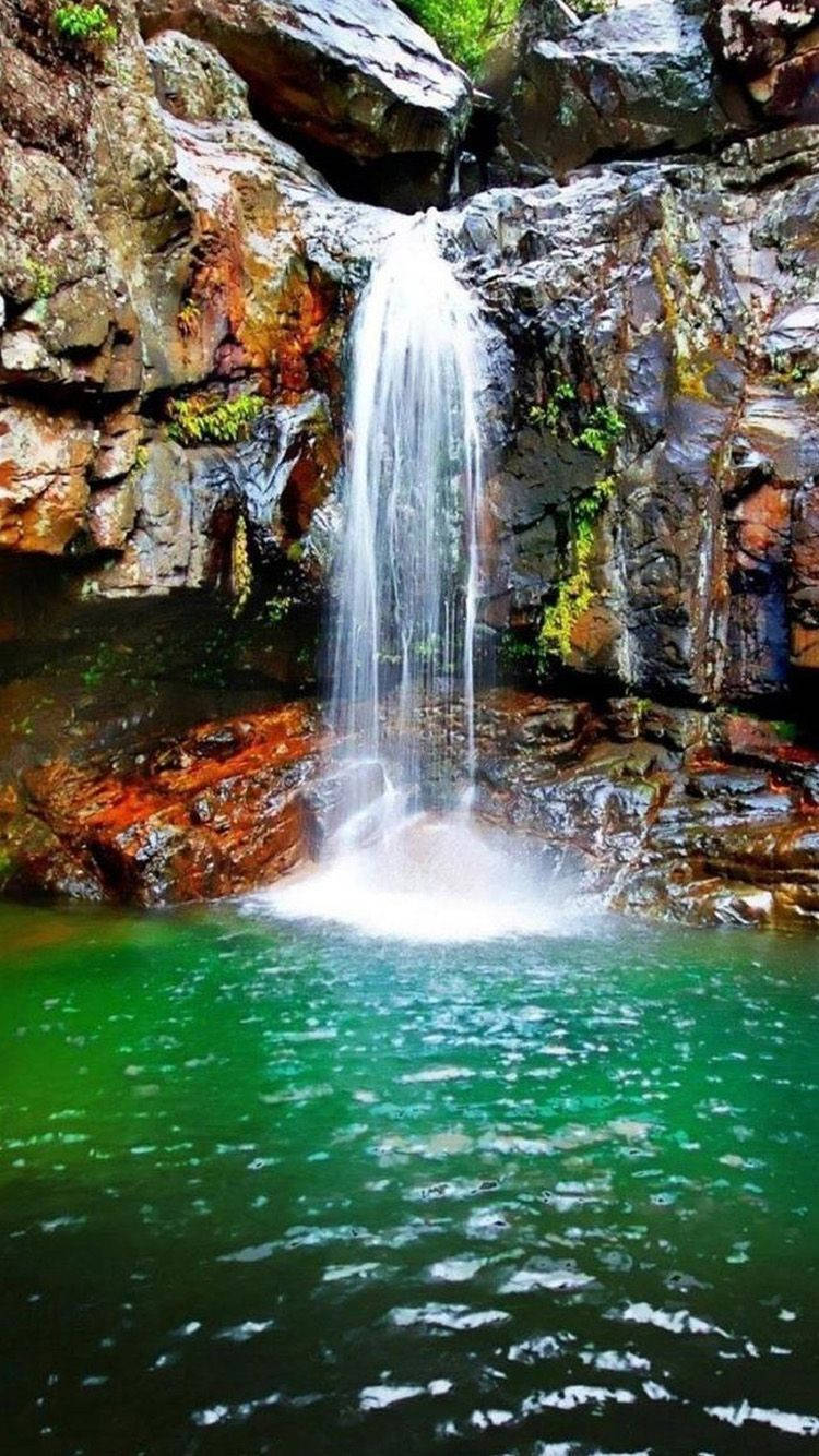 A waterfall in a rocky mountain setting with a pool of water below. - Waterfall