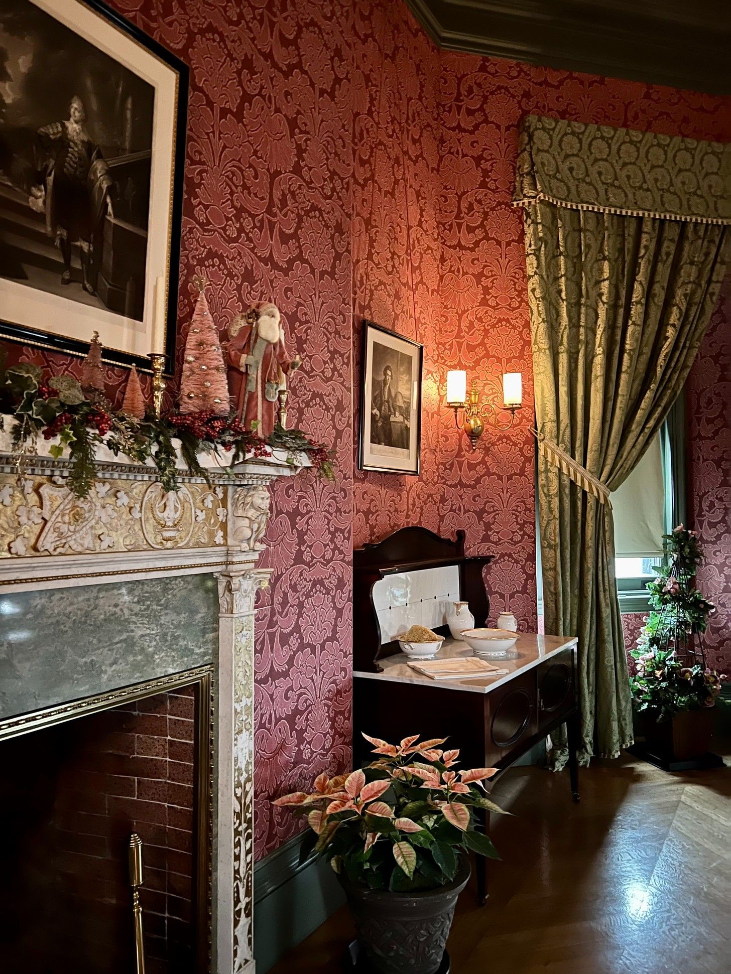 A red room with a fireplace and a potted plant. - Bridgerton