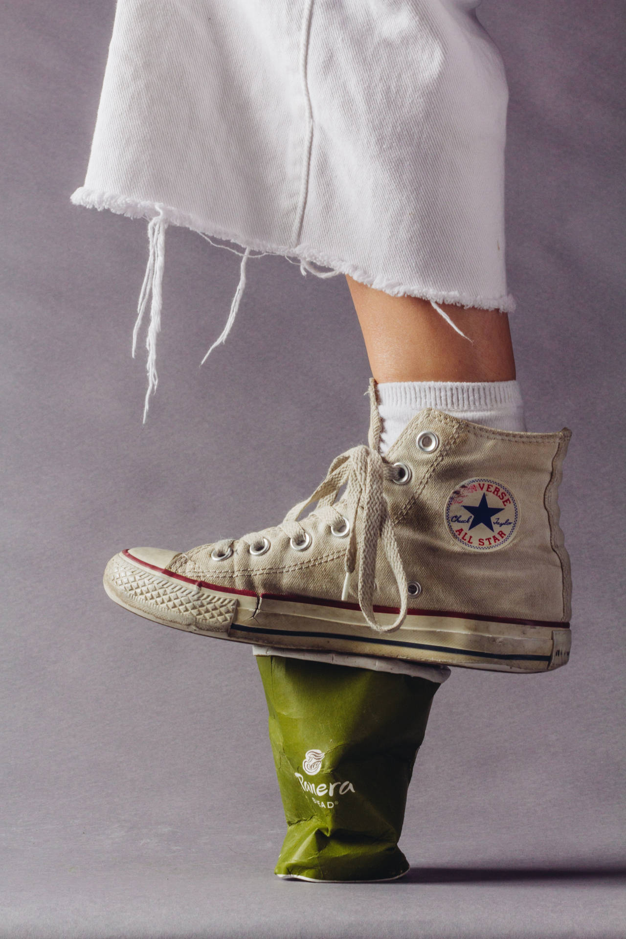 A model wearing white converse sneakers with a green cone on the heel - Converse