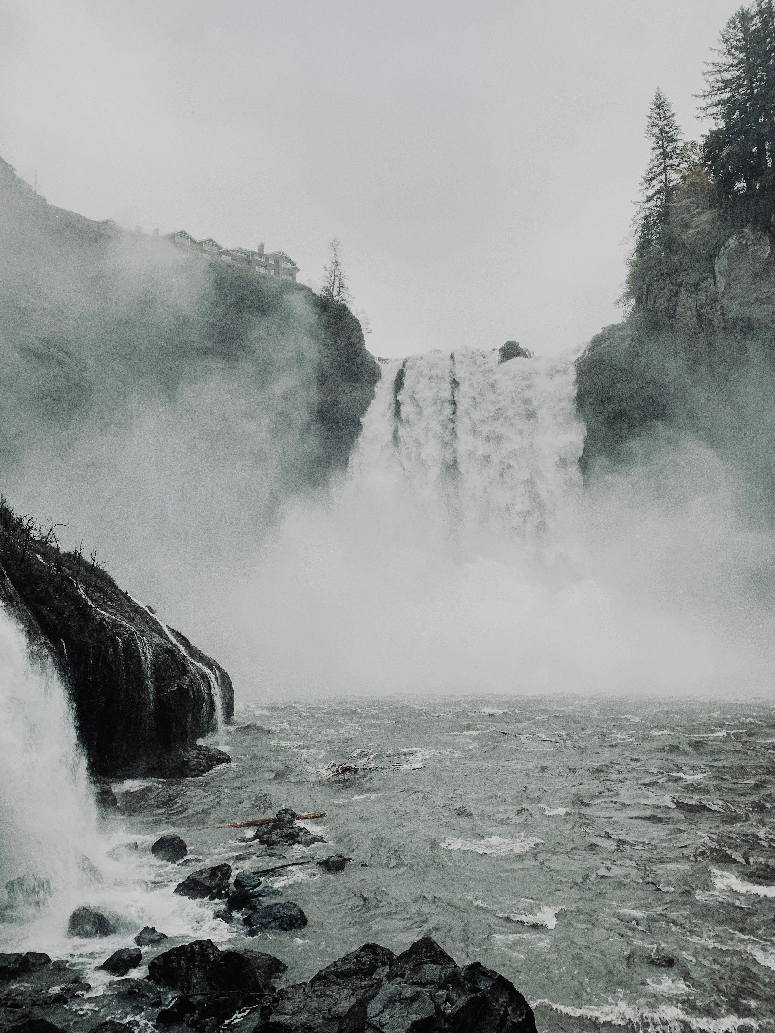 In the image, a waterfall is creating mist over the shore, creating a serene and misty atmosphere. - Waterfall