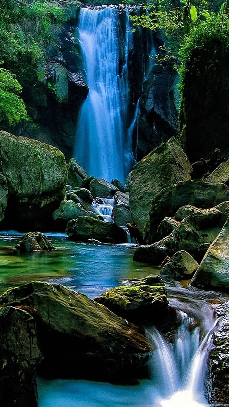 A waterfall surrounded by rocks and trees. - Waterfall