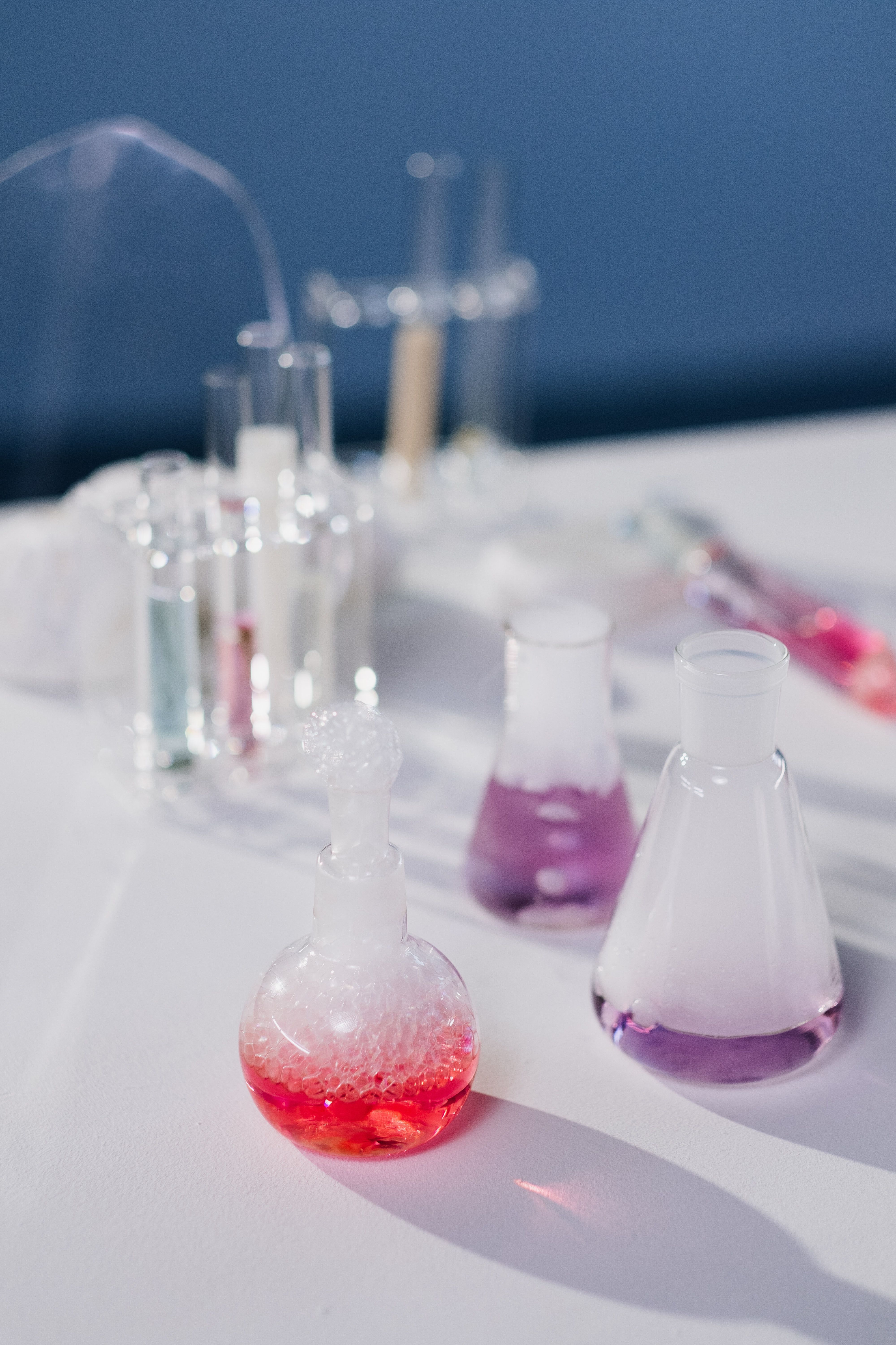 A close up of a few beakers with red liquid in one and purple liquid in another. - Chemistry