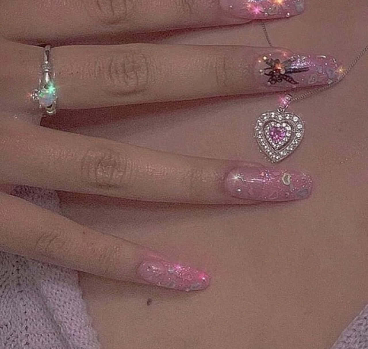 A woman's hands with long, pointed nails painted in pink glitter - Nails