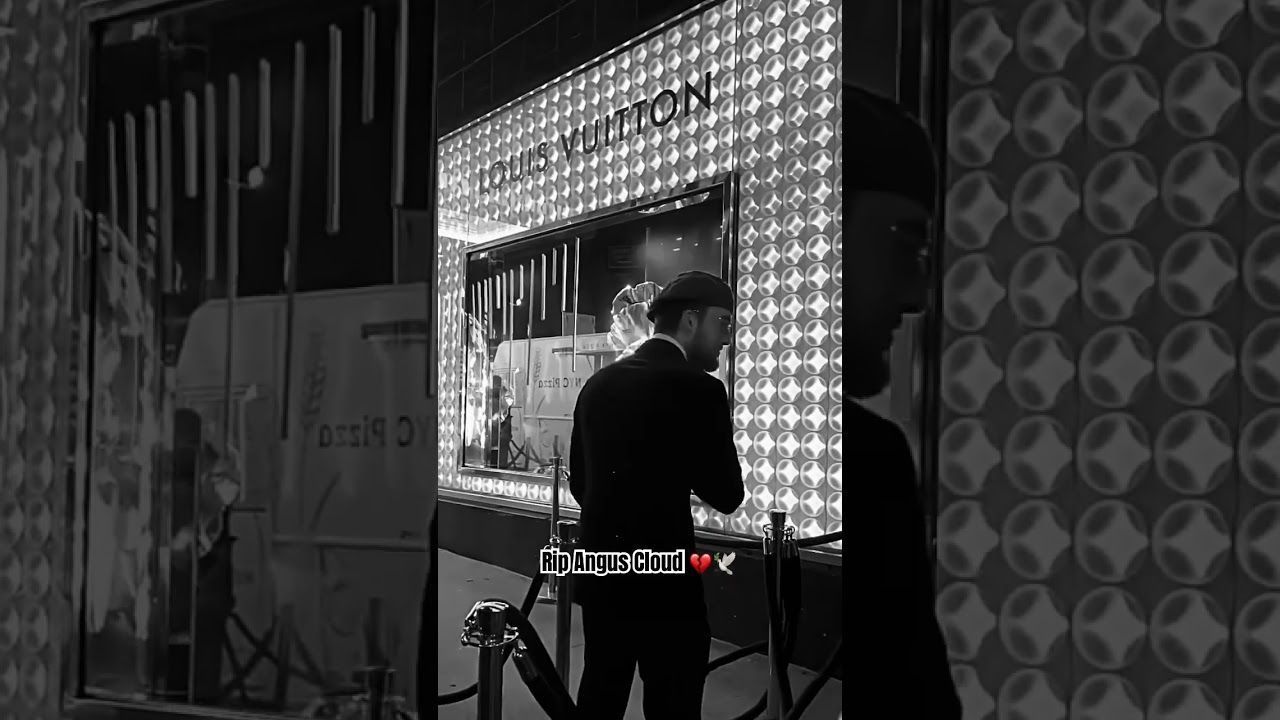 A man looking at a Louis Vuitton store window. - Angus Cloud