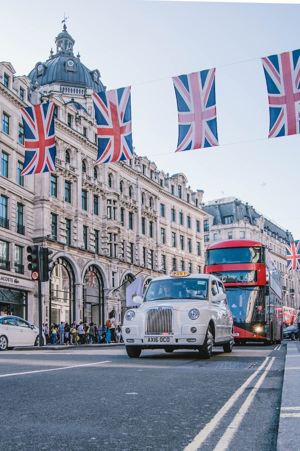 A taxi driving down the street with flags flying - London