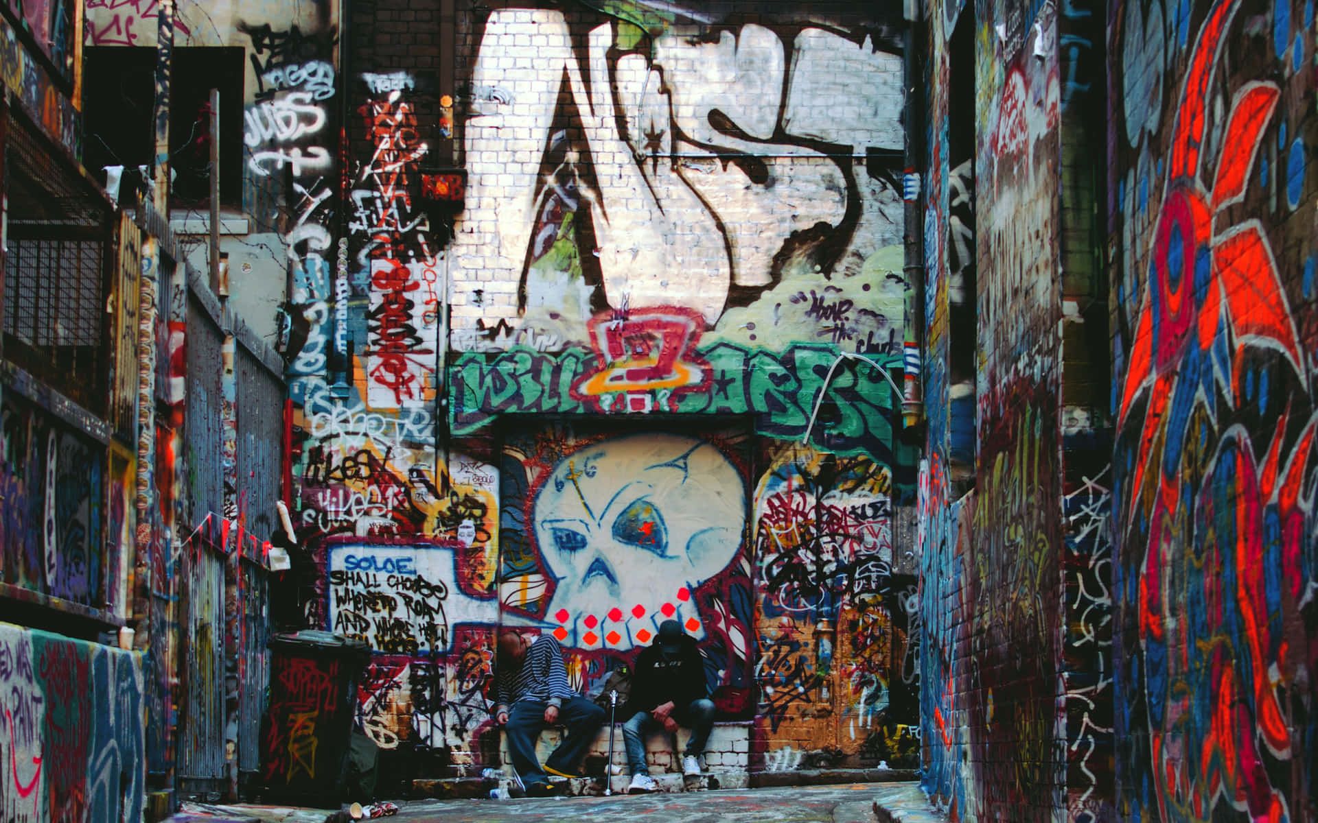 Two people sitting on a bench in a graffiti-covered alleyway - Street art
