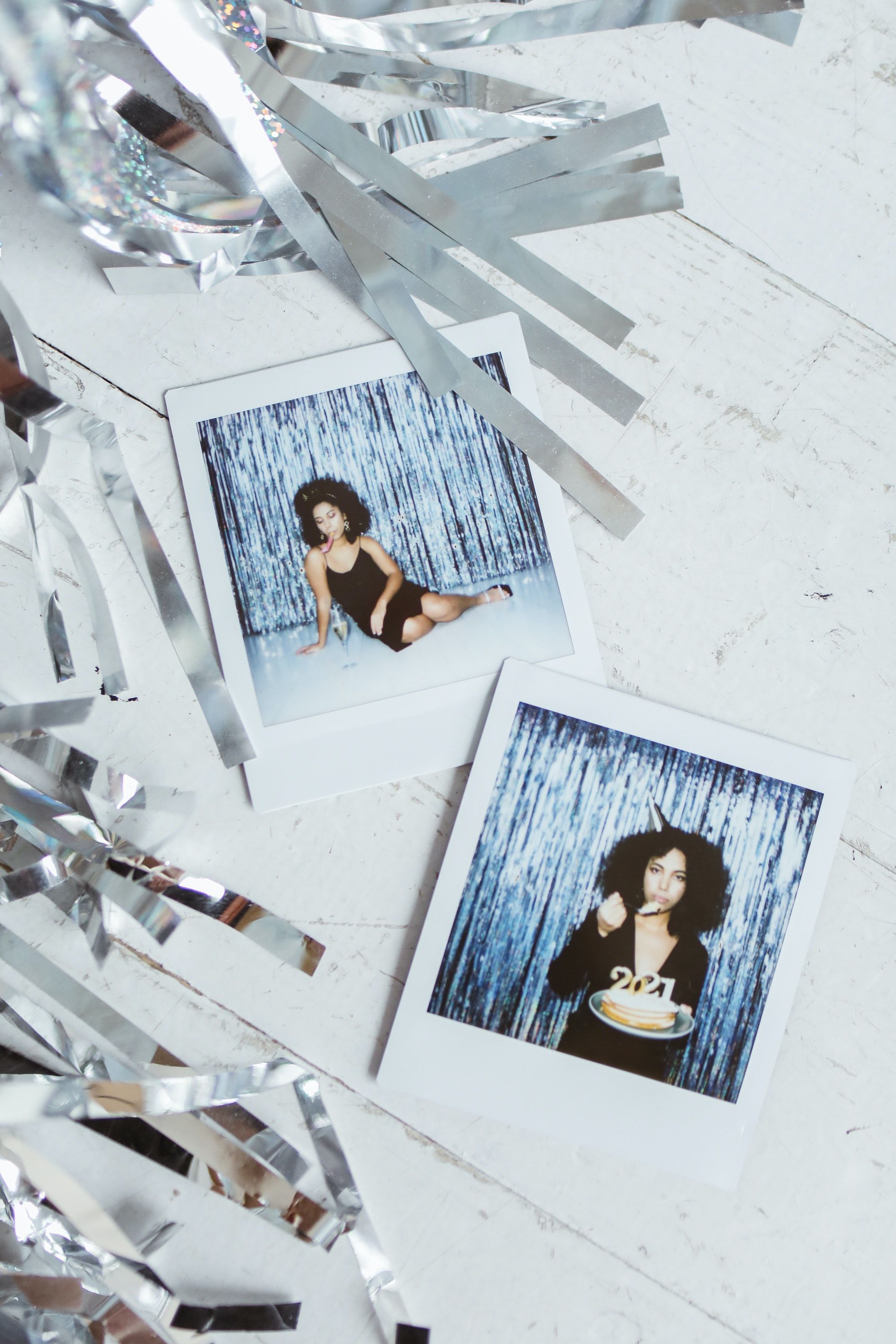 Polaroid photos of a woman in a black swimsuit and a black bodysuit on a white background with silver streamers - Polaroid
