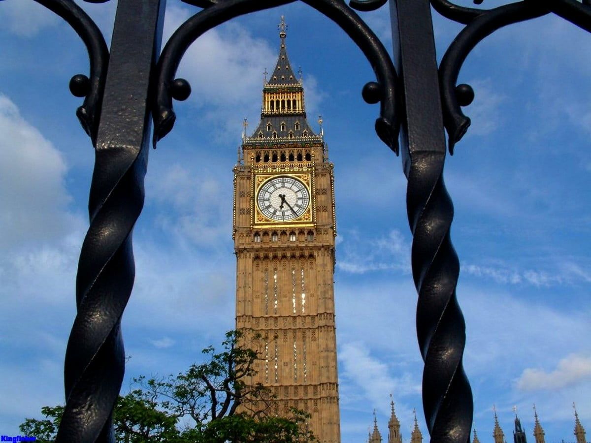 A large clock tower with a metal gate in the foreground. - London