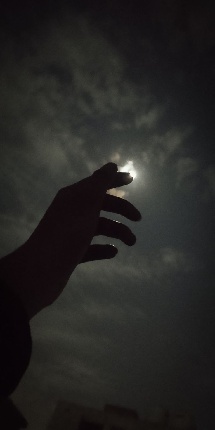 A hand is reaching for the moon in the sky. - Shadow