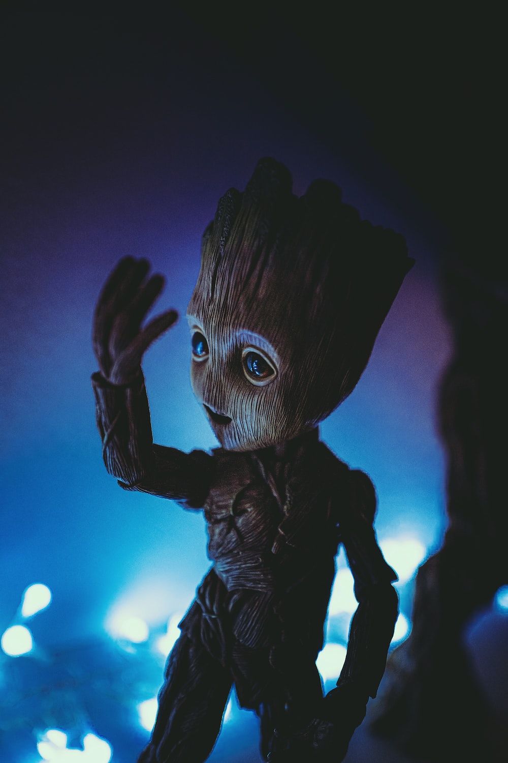 A Guardians of the Galaxy toy of Groot in a blue and black background - Avengers