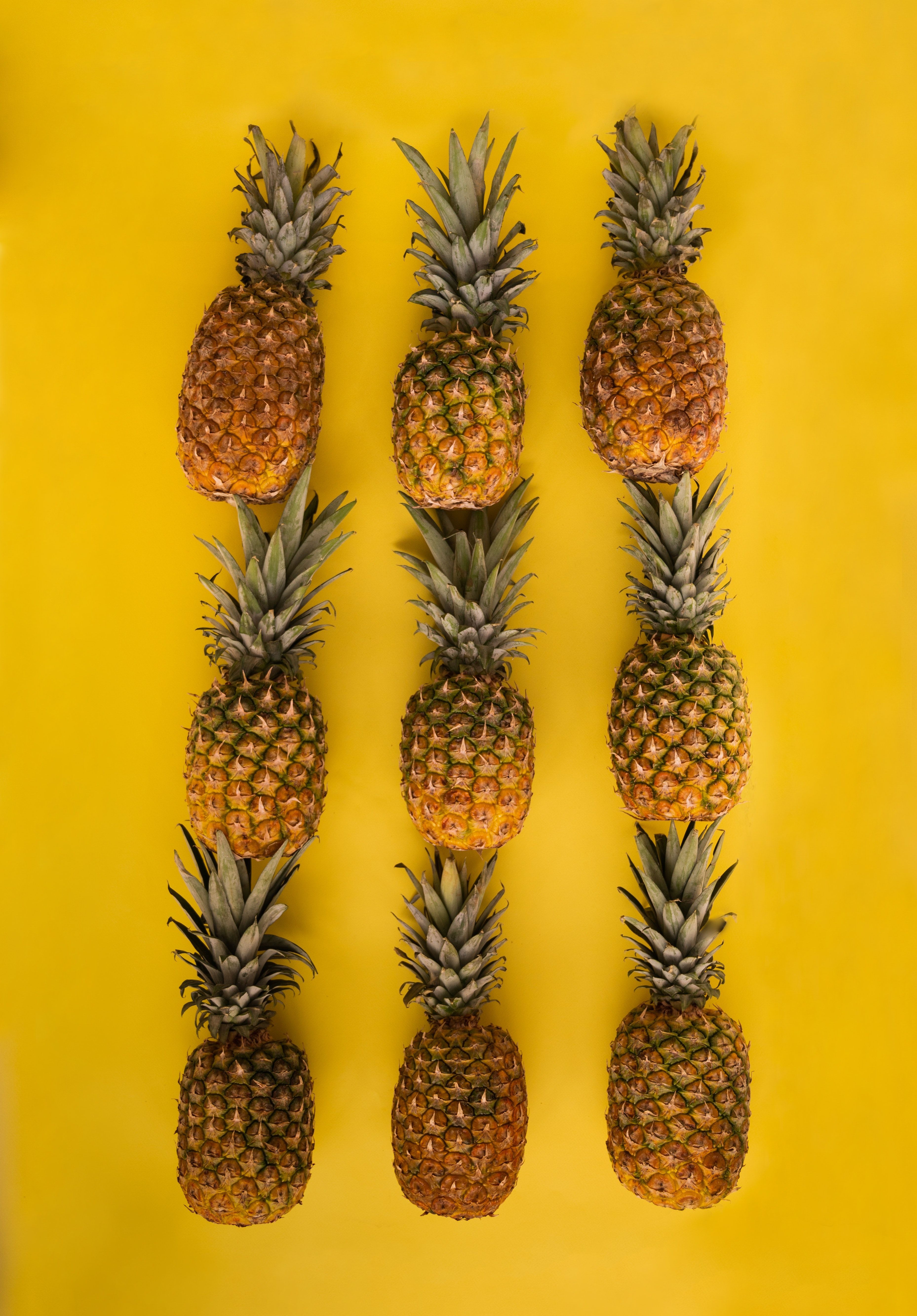 Arrangement of pineapples on yellow surface · Free